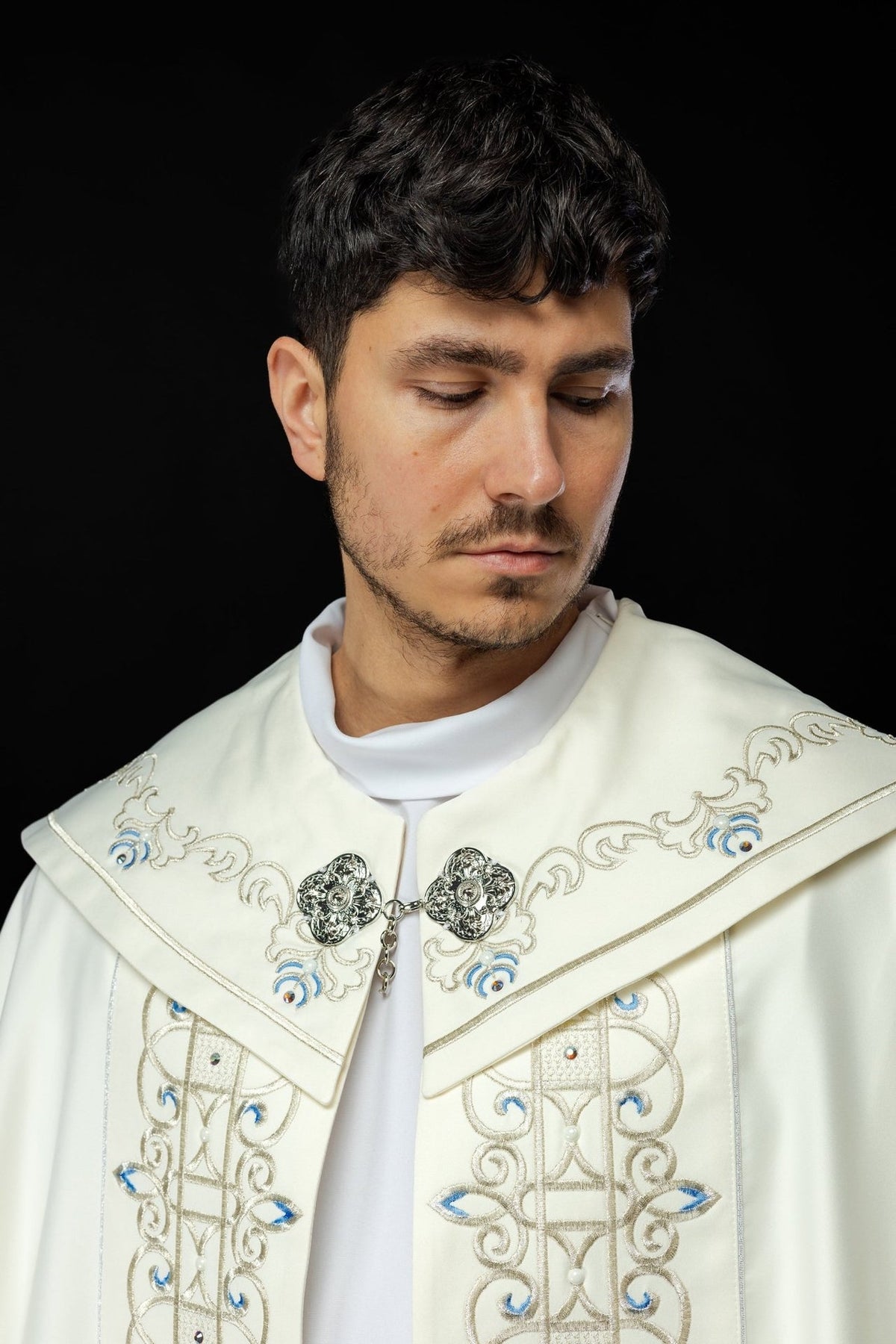Ivory cope shoulder close-up with gold embroidery and blue motifs