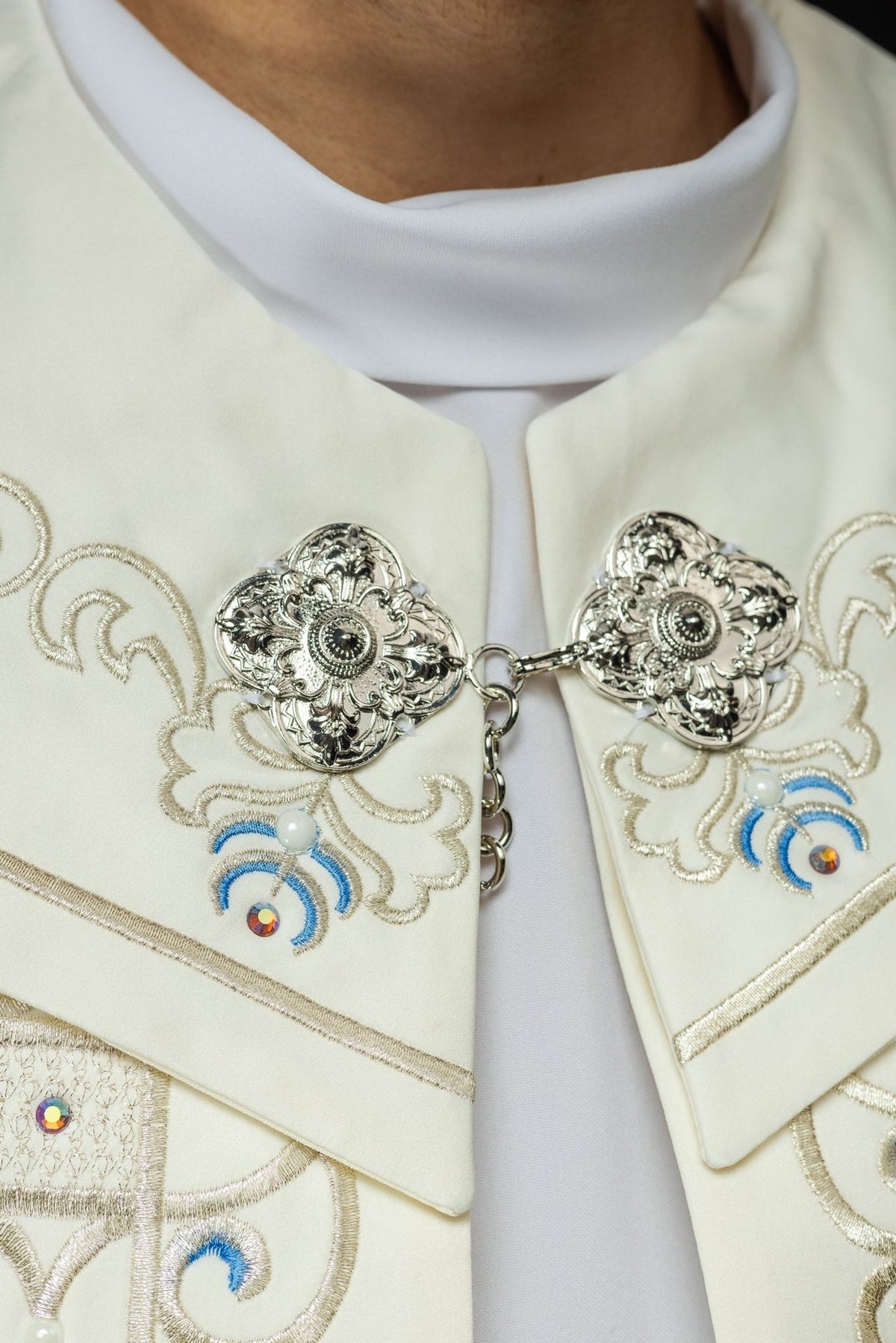 Cope close-up showing silver clasp, ivory fabric and embroidered blue motifs