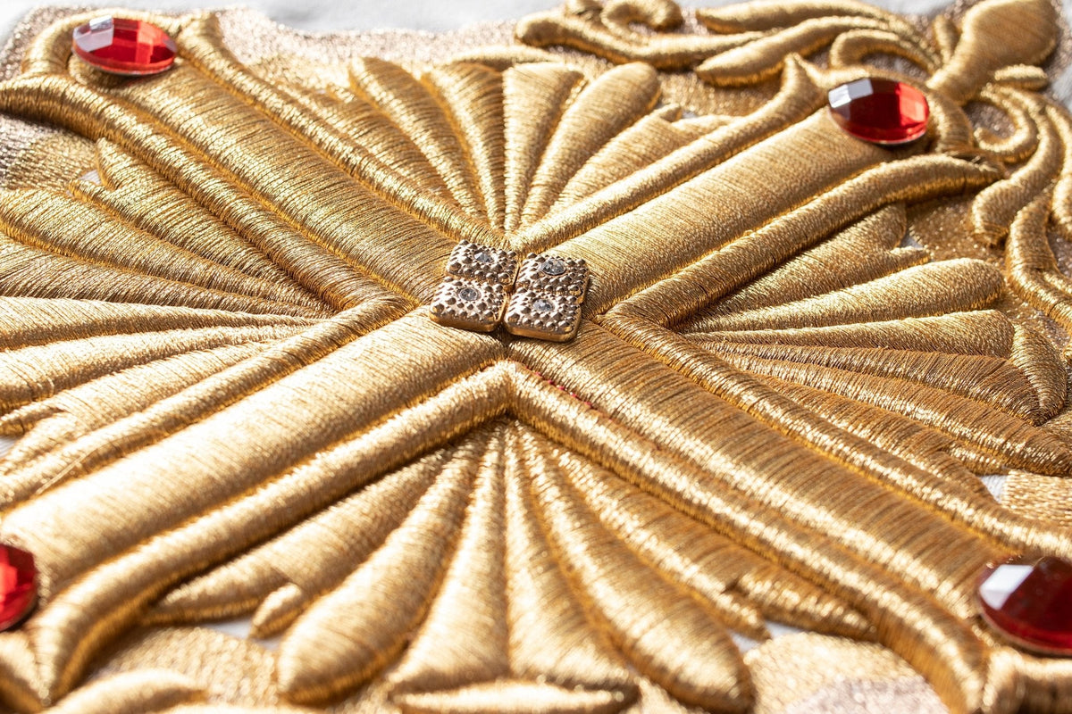 Detailed gold cross embroidery with raised stitching and red accents