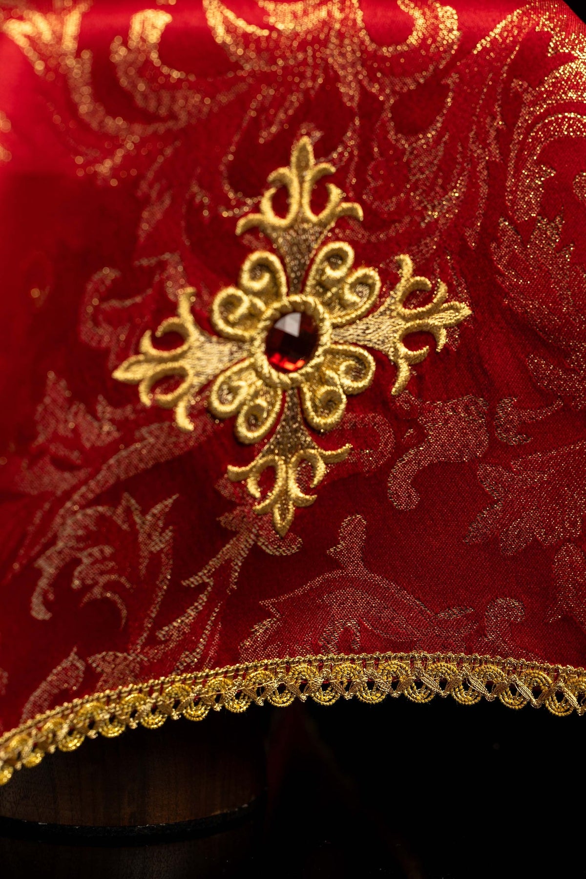 Chalice veil close-up showing embroidered cross with red stone and gold trim