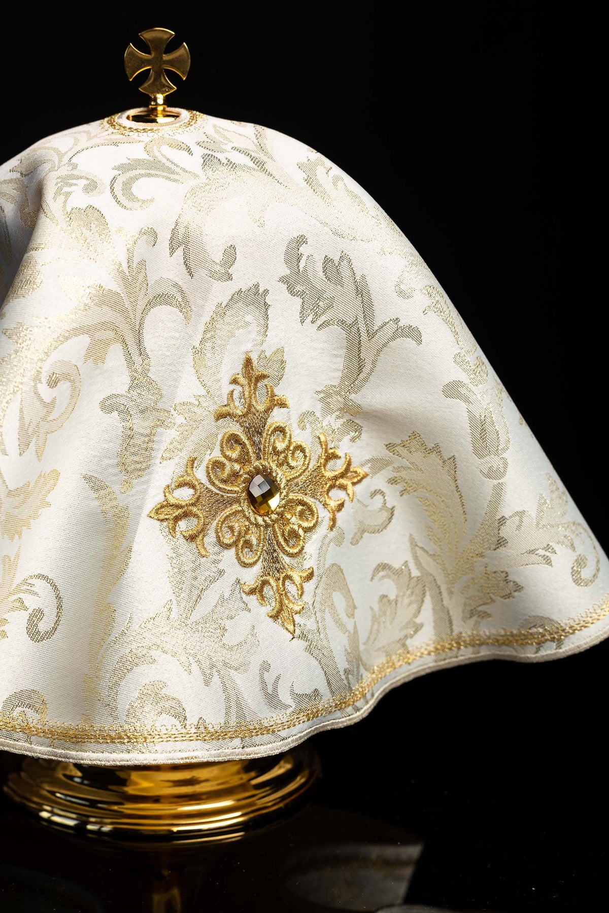 Ecru ciborium veil close-up with gold cross embroidery, patterned fabric, and stone