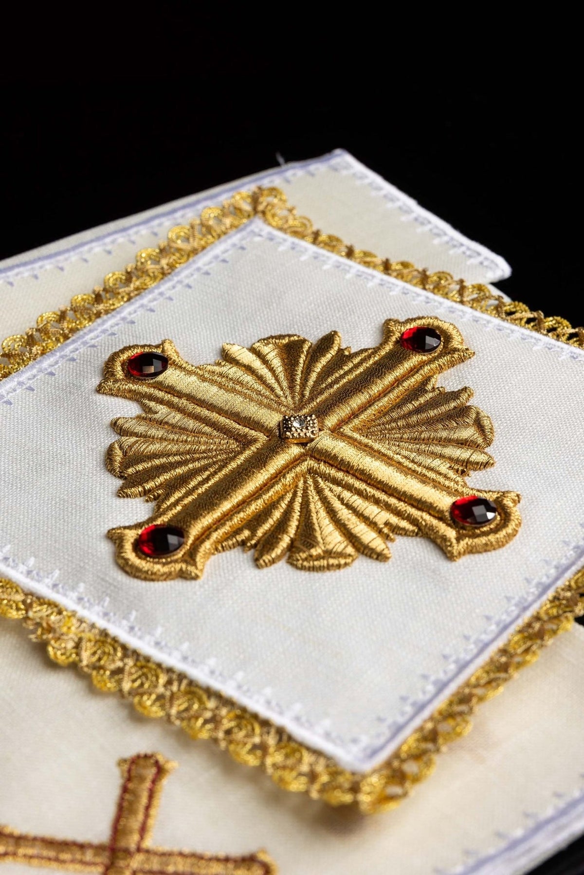 Altar linen set close-up showing a gold embroidered cross with red stones and gold trim