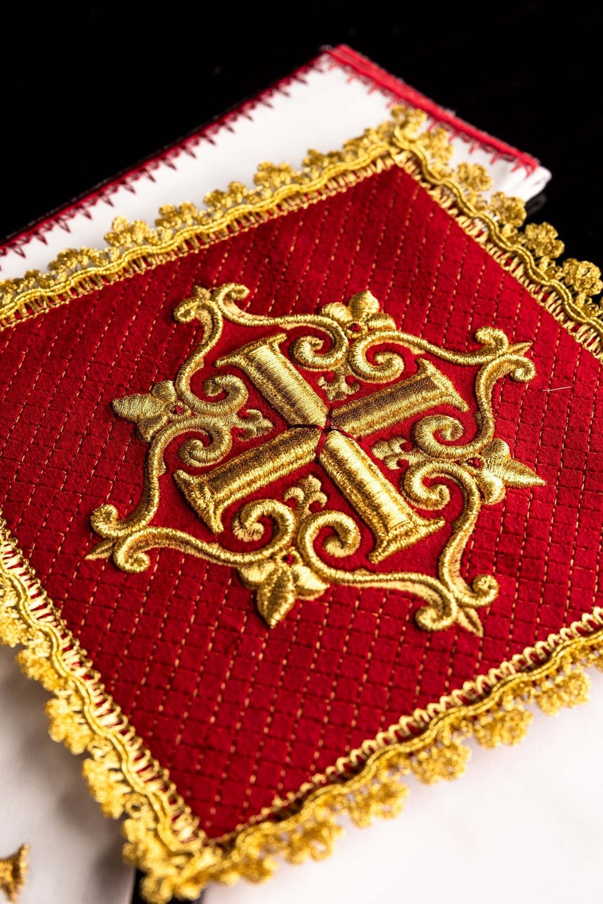 Altar linen set close-up showing red velvet chalice pall with gold embroidered cross and ornate trim