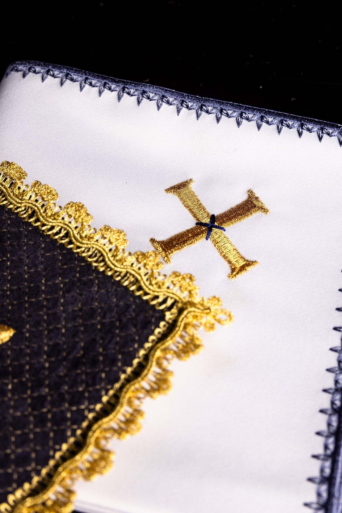 Altar linen set detail showing white linen with gold embroidered cross and blue edging