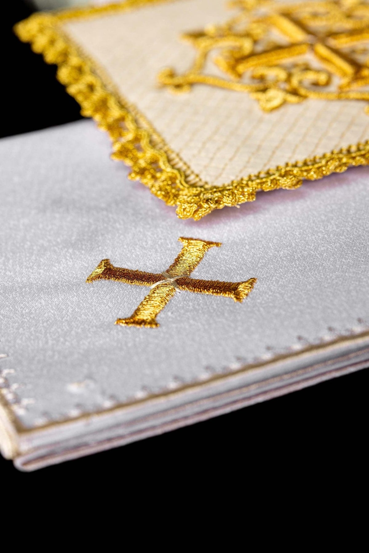Altar linen set detail showing gold embroidered cross on folded white linen