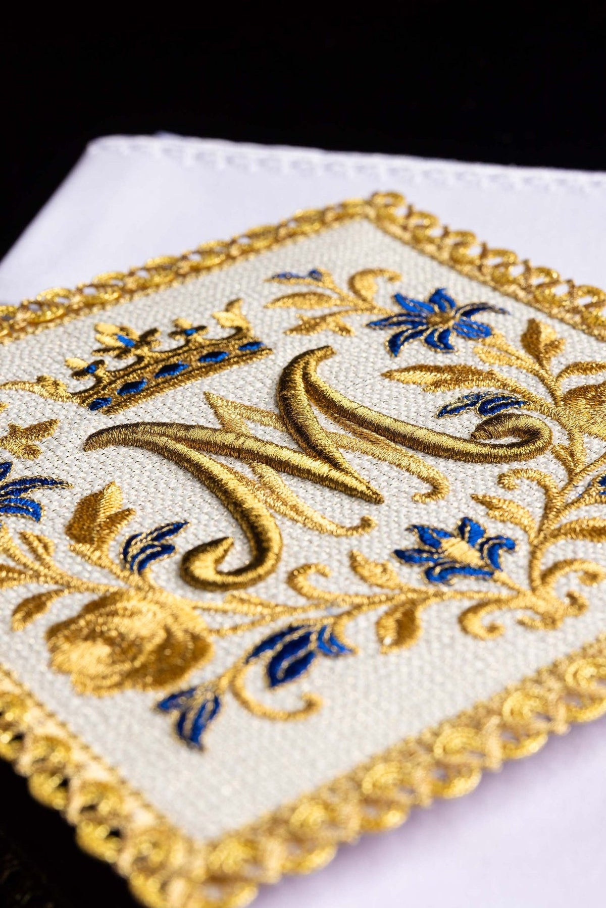 Altar linen set close-up of white fabric with gold Marian monogram embroidery