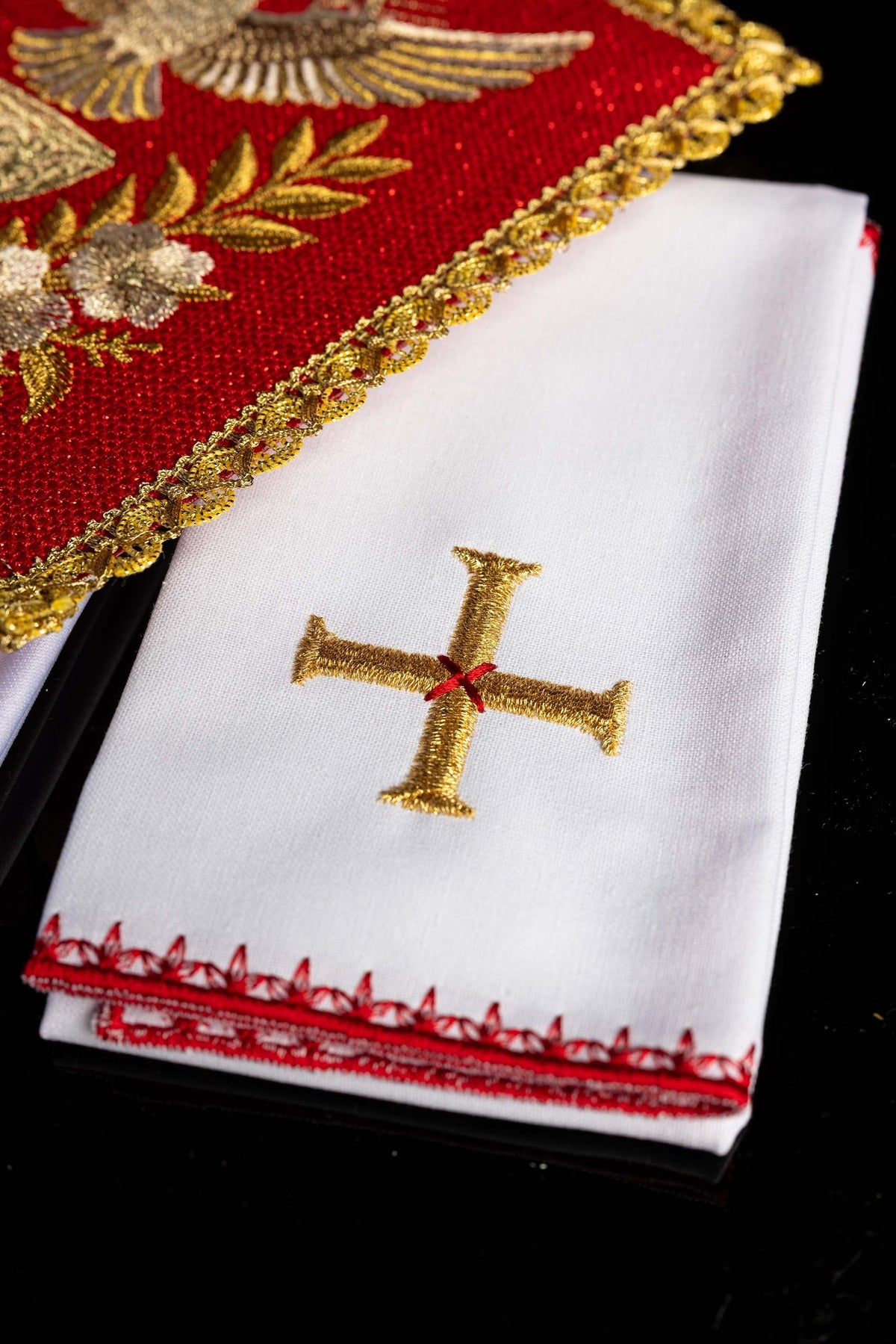 Altar linen set detail showing gold embroidered cross and red decorative edging