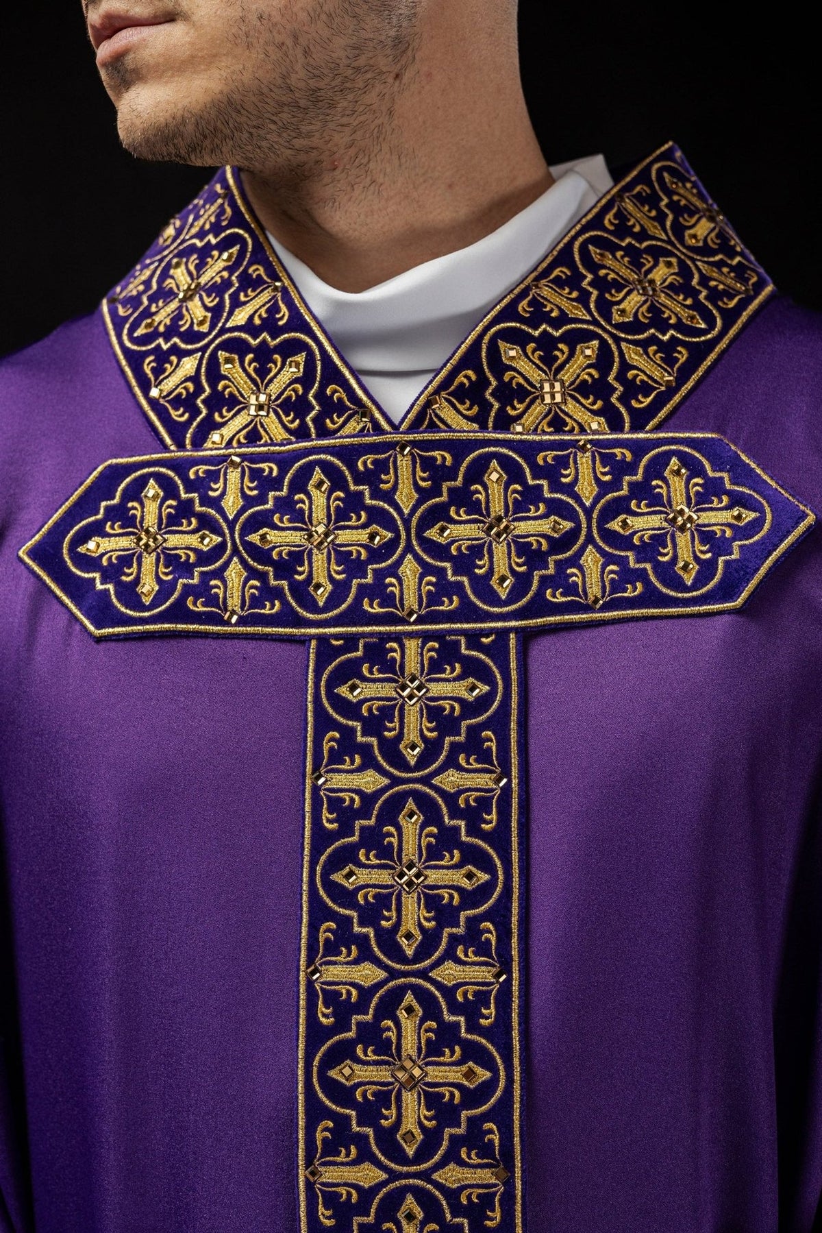 Purple chasuble close-up showing decorative stones on the embroidered collar and cross orphrey
