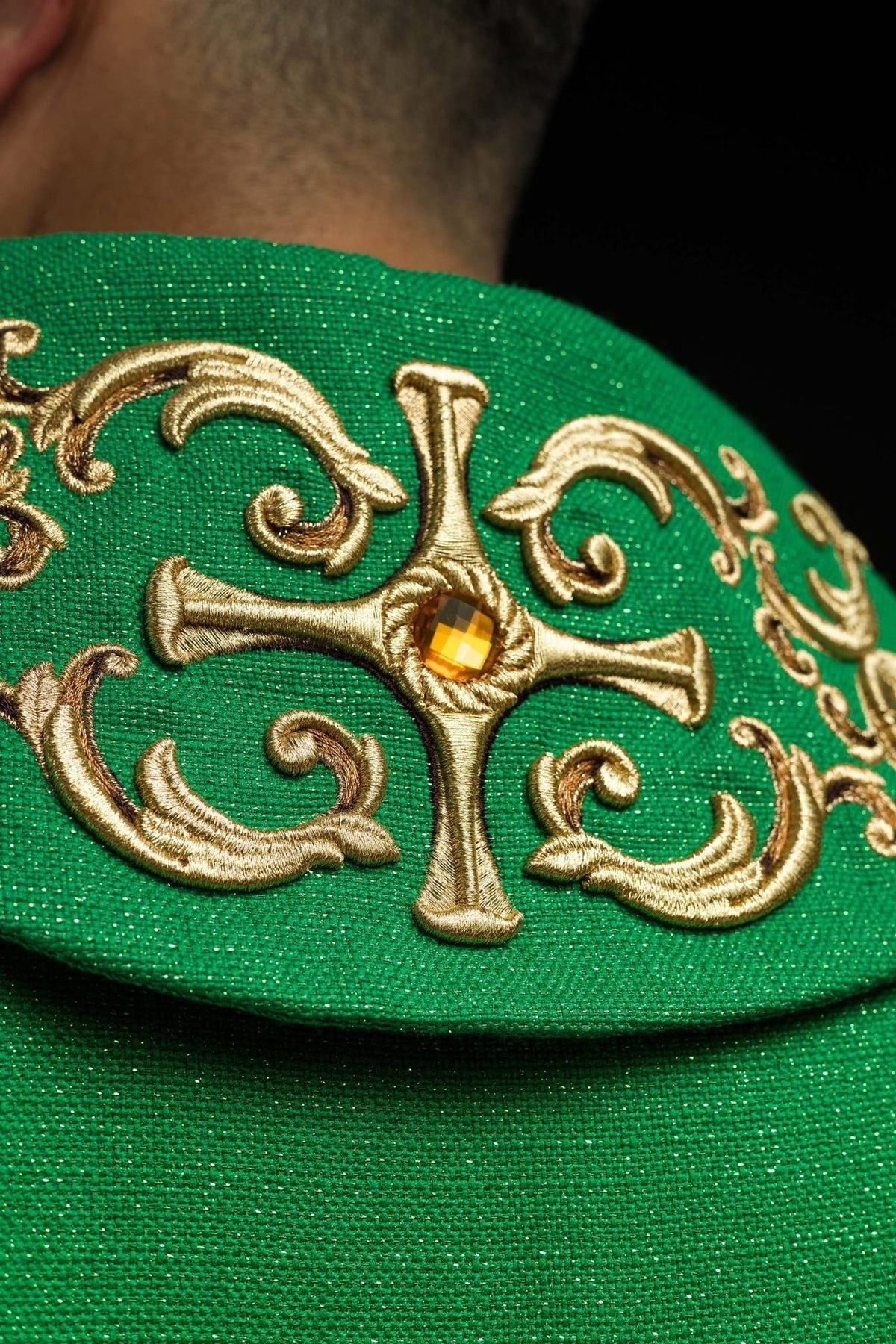 Green chasuble close-up of embroidered gold cross and green fabric