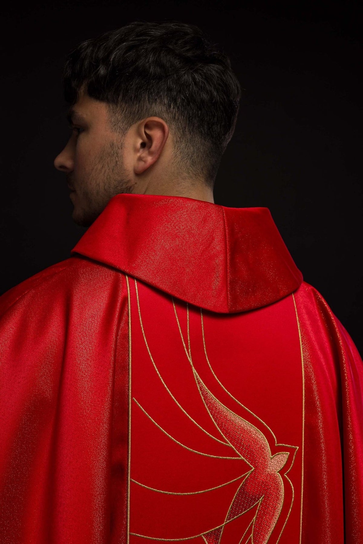 Red chasuble close-up showing shimmering polyester fabric and gold sleeve trim
