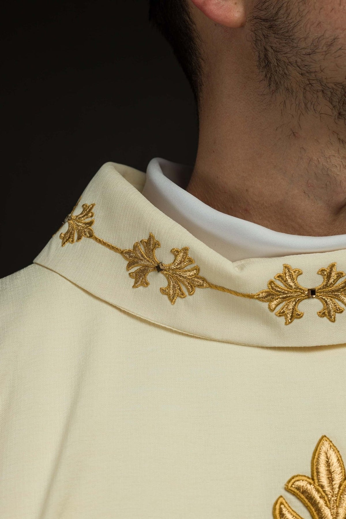 Embroidered chasuble close-up showing ivory stand-up collar with gold leaf motifs and stones
