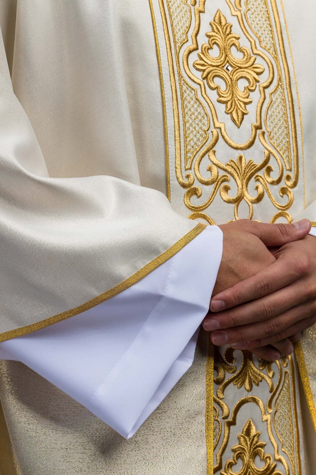 White chasuble close-up showing gold trim, embroidered orphrey and sleeve edge