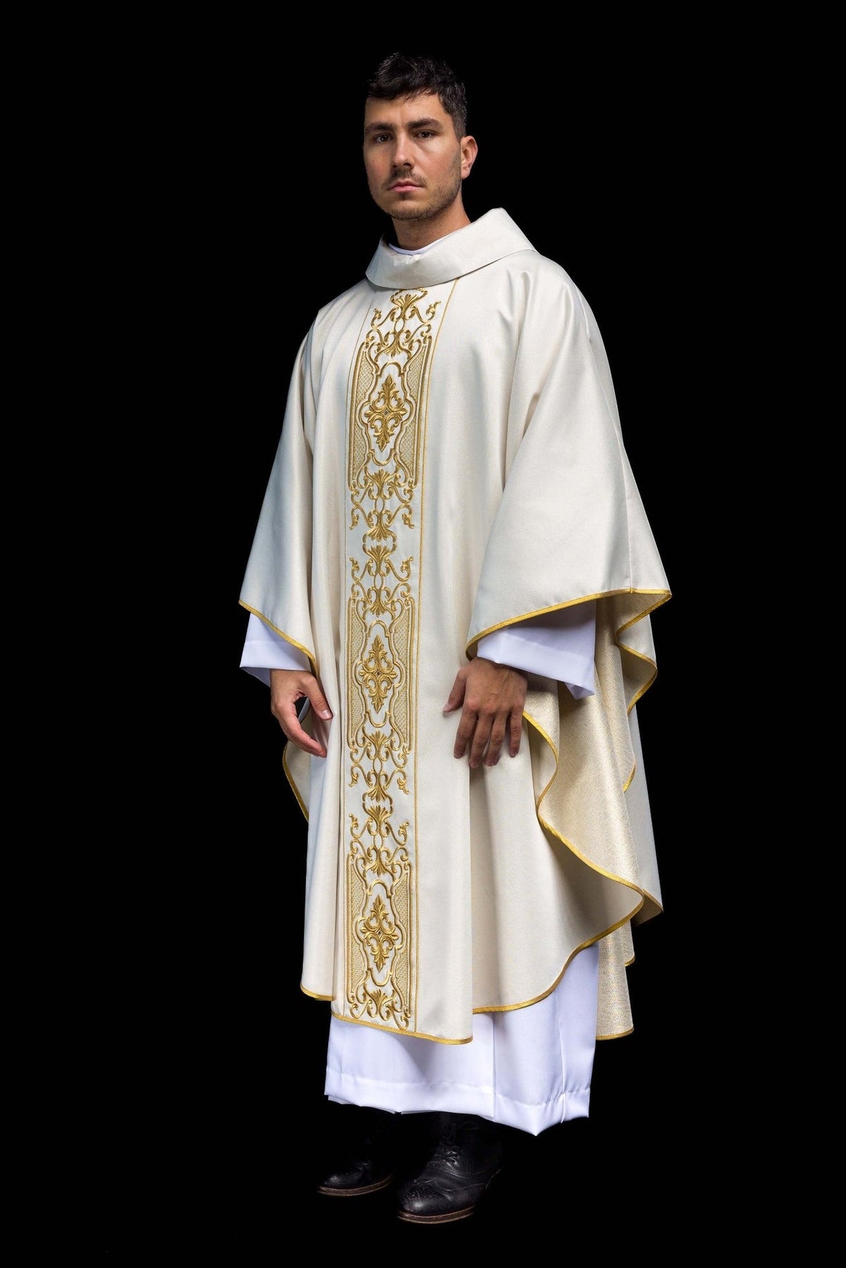 White chasuble side view showing flowing fabric, gold trim and embroidered front orphrey