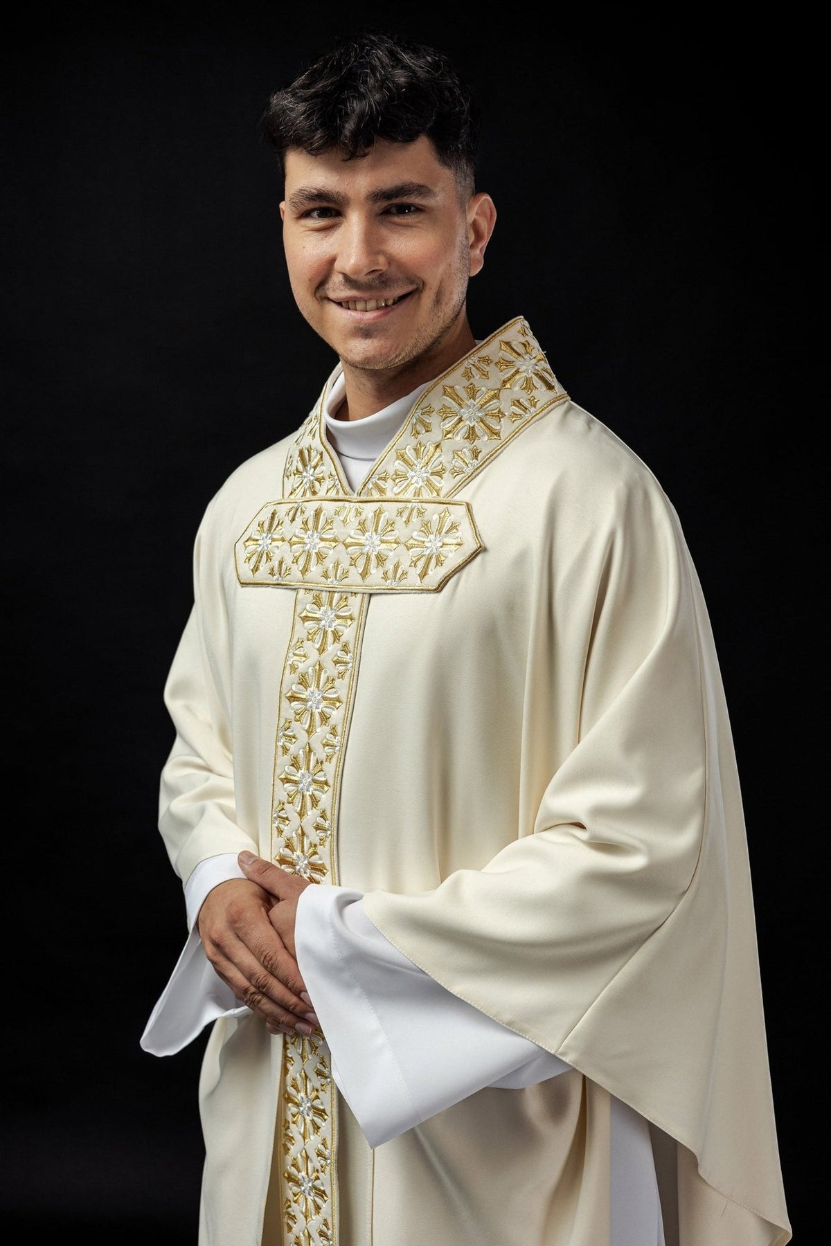 Ecru chasuble worn, close front view of gold and white cross embroidery