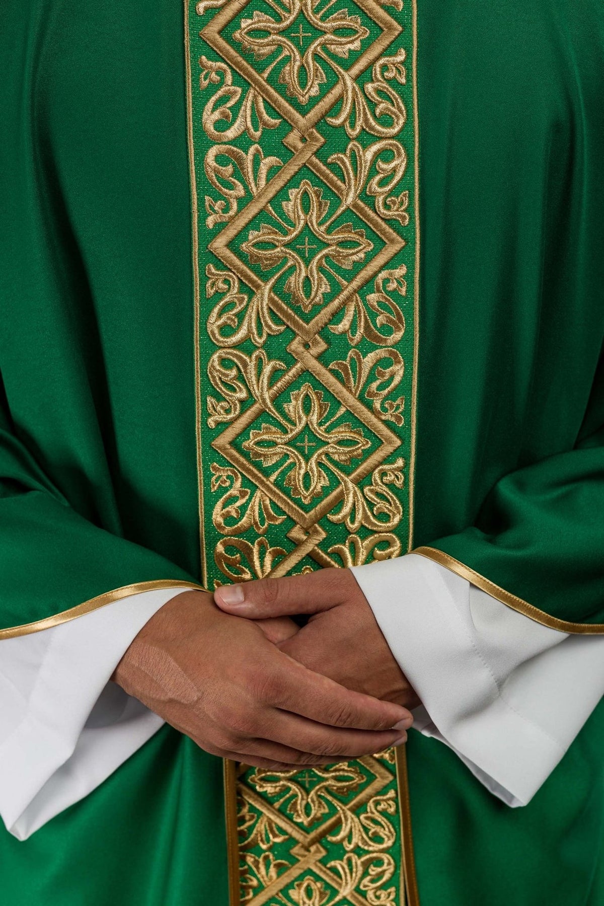 Green chasuble close-up showing embroidered gold crosses and floral motifs