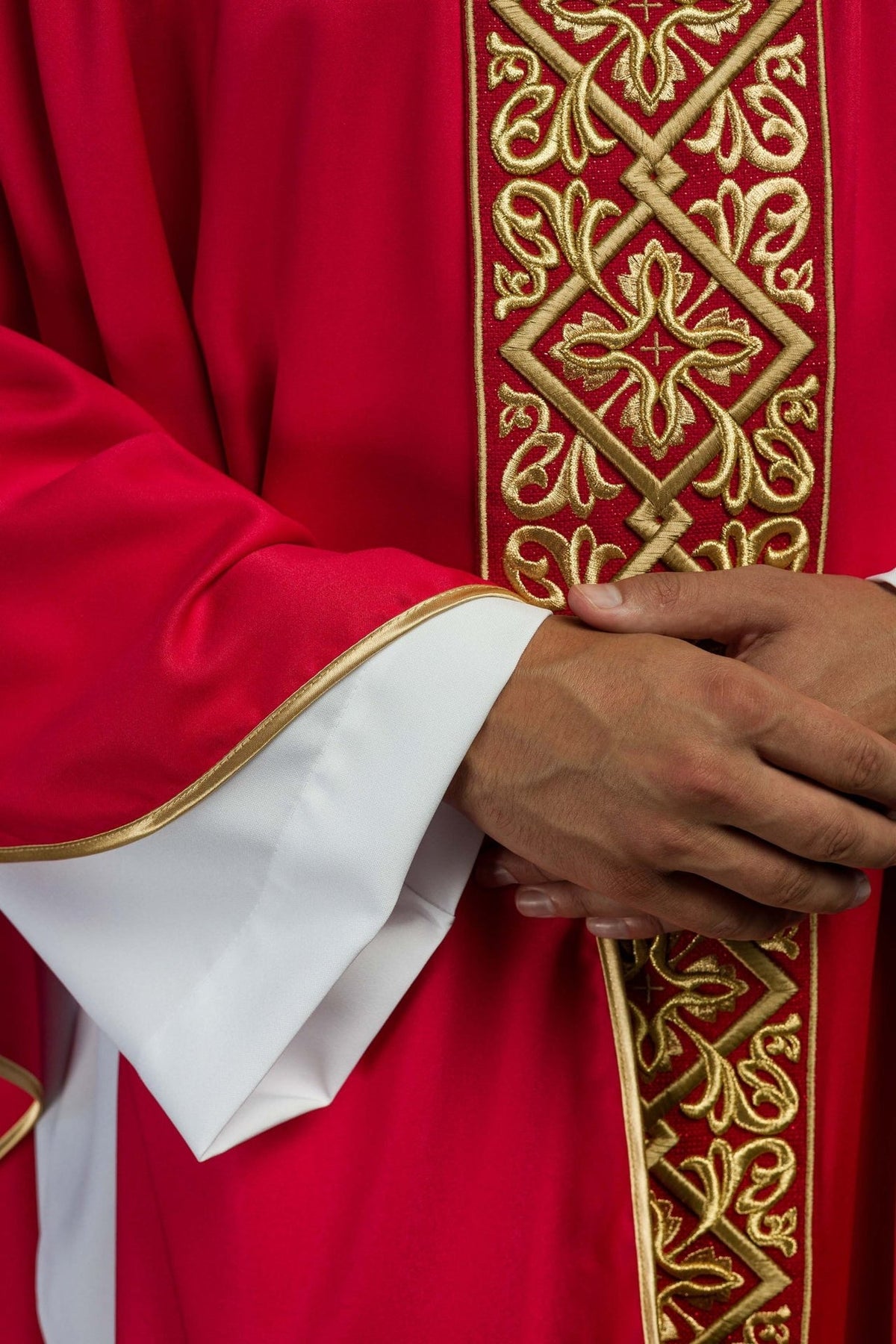 Red chasuble detail showing gold embroidered front panel and satin sleeve trim
