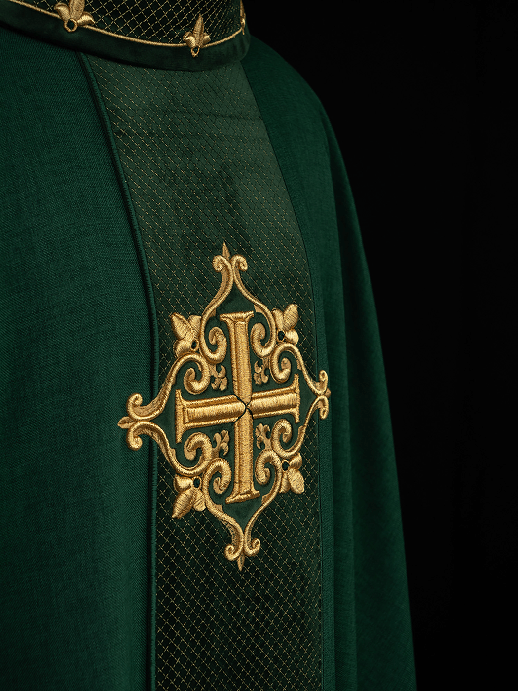 Green chasuble close-up with gold embroidered cross on a diamond-patterned panel
