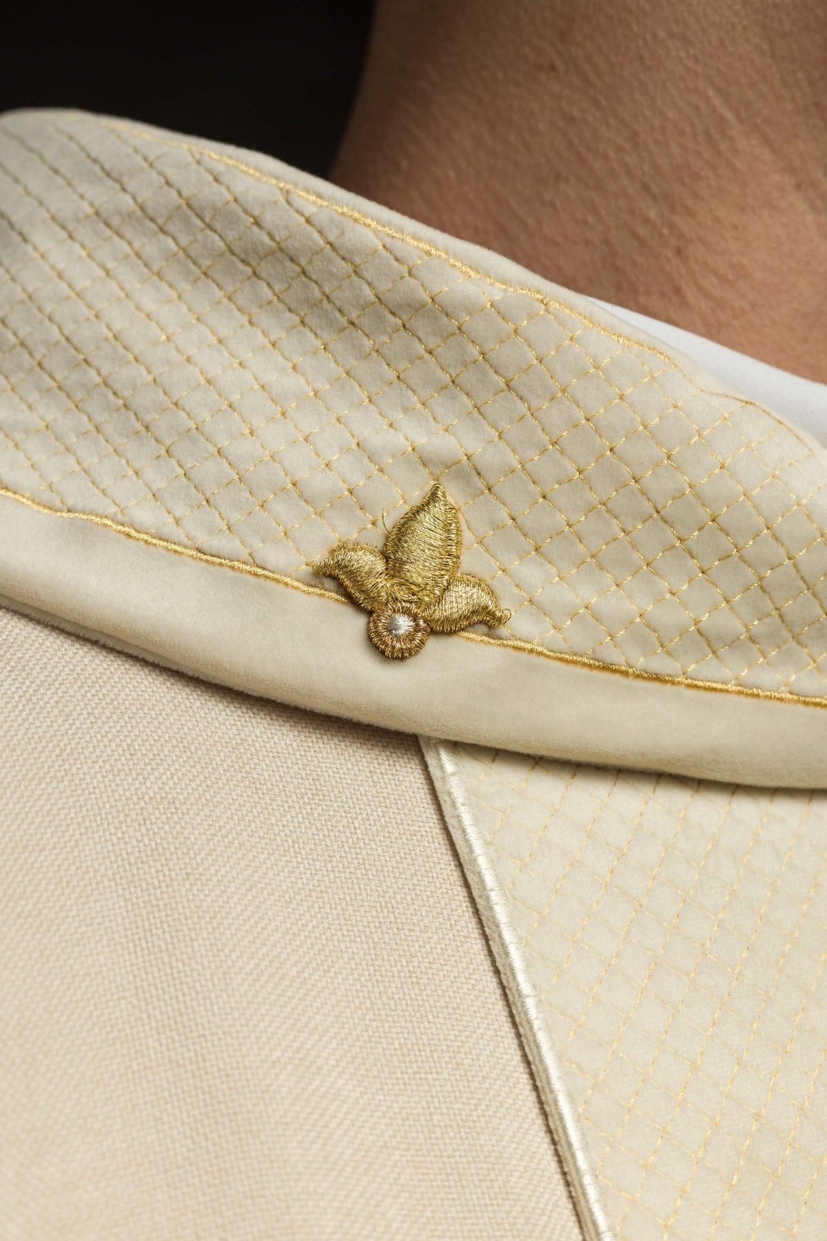 Ecru chasuble detail showing gold cross embroidery and diamond-patterned front panel
