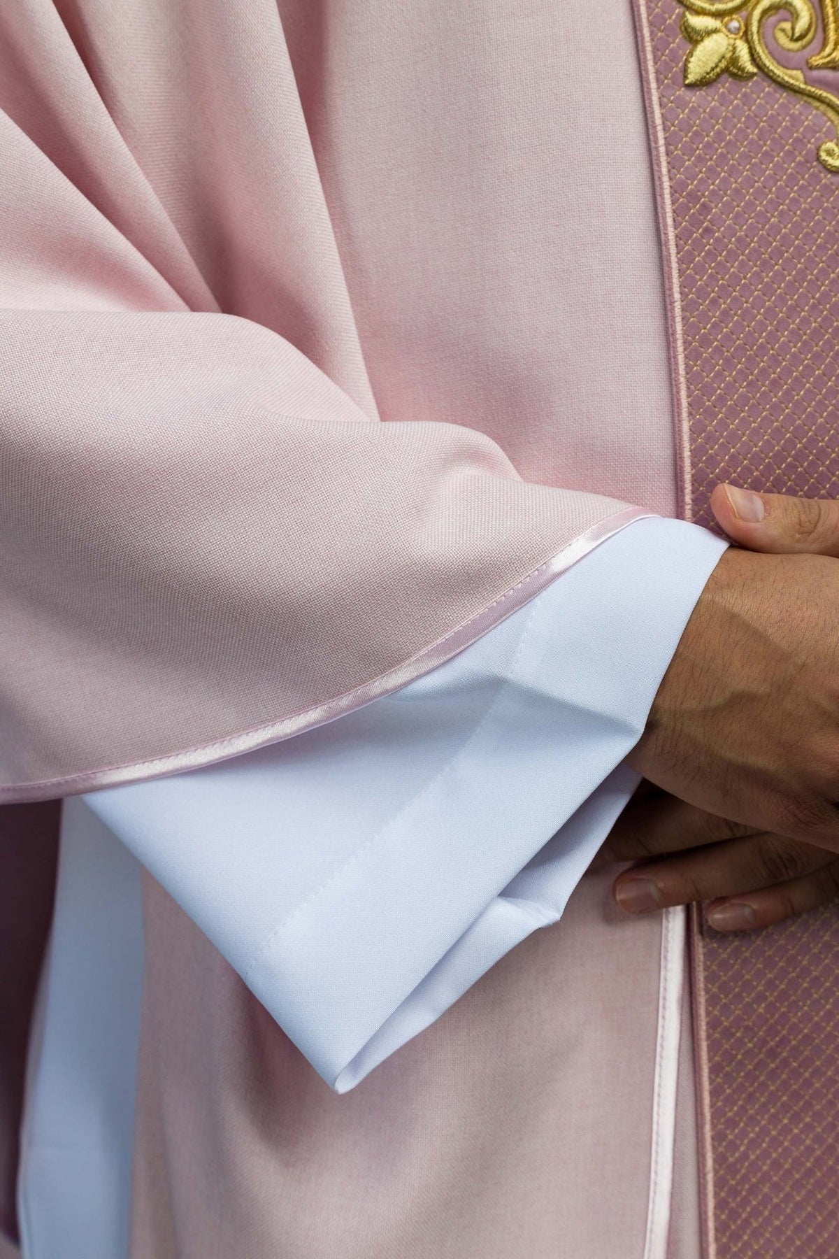 Pink chasuble sleeve close-up with satin trim and white lining