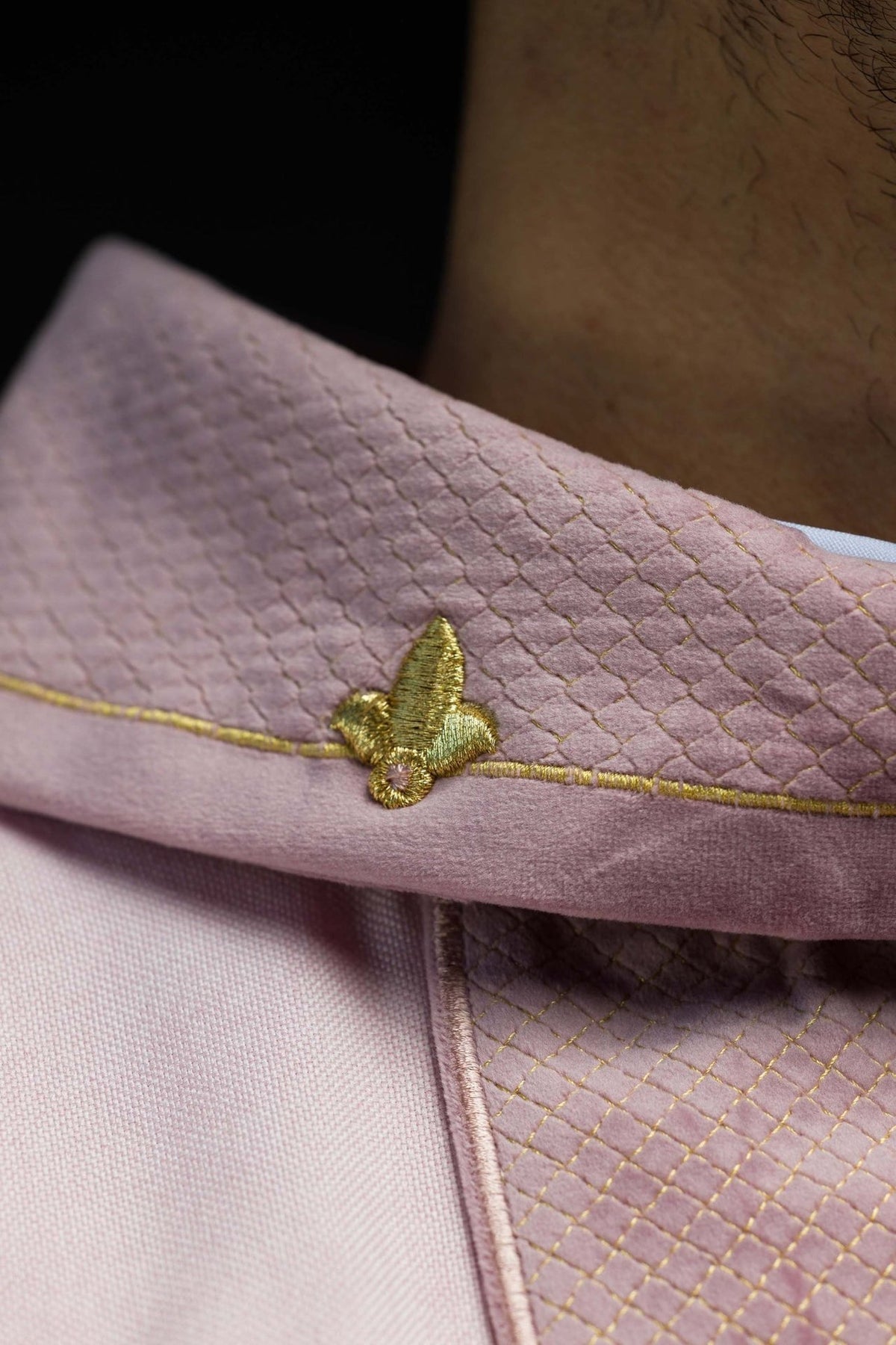 Pink velvet fabric stand-up collar close-up with gold embroidered motif