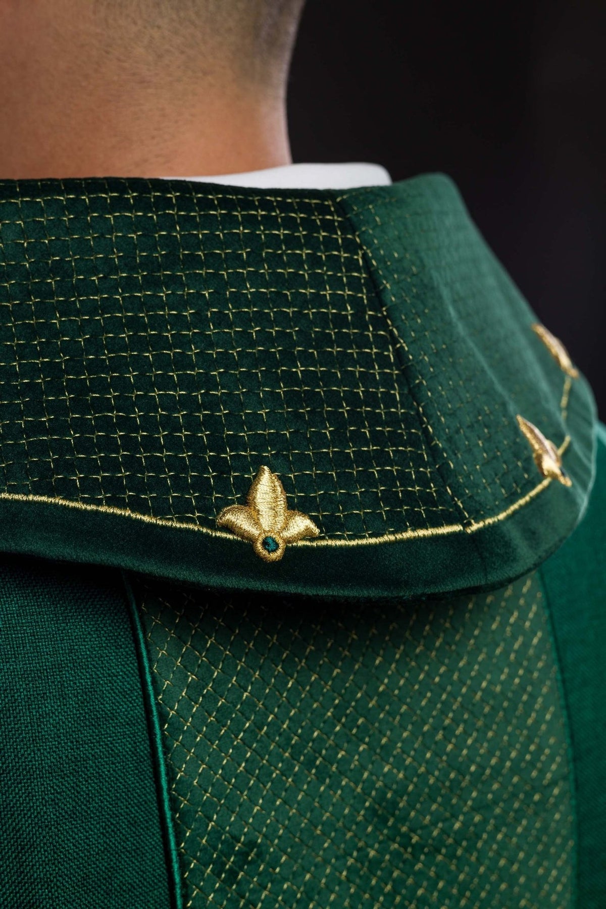 Close-up of green stand-up collar with gold trim and embroidered motifs