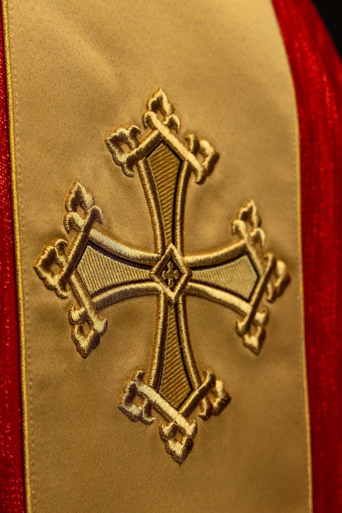 Red chasuble close-up showing gold cross embroidery