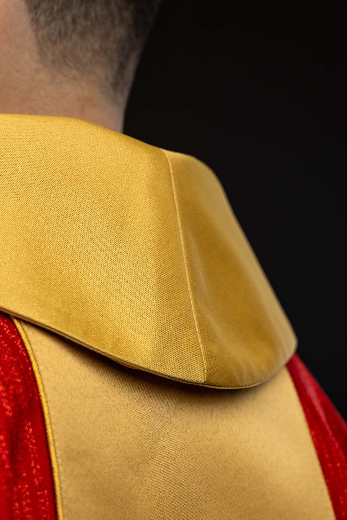 Red chasuble close-up showing gold orphrey and sleeve trim