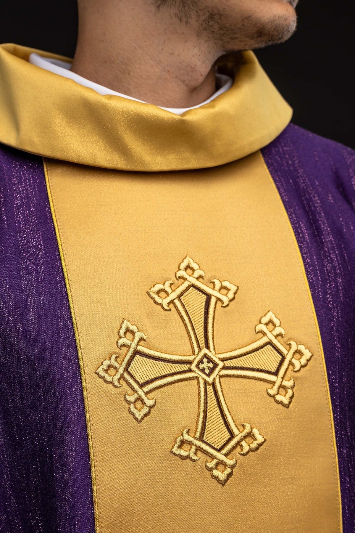 Purple chasuble close-up showing gold stand-up collar and embroidered cross