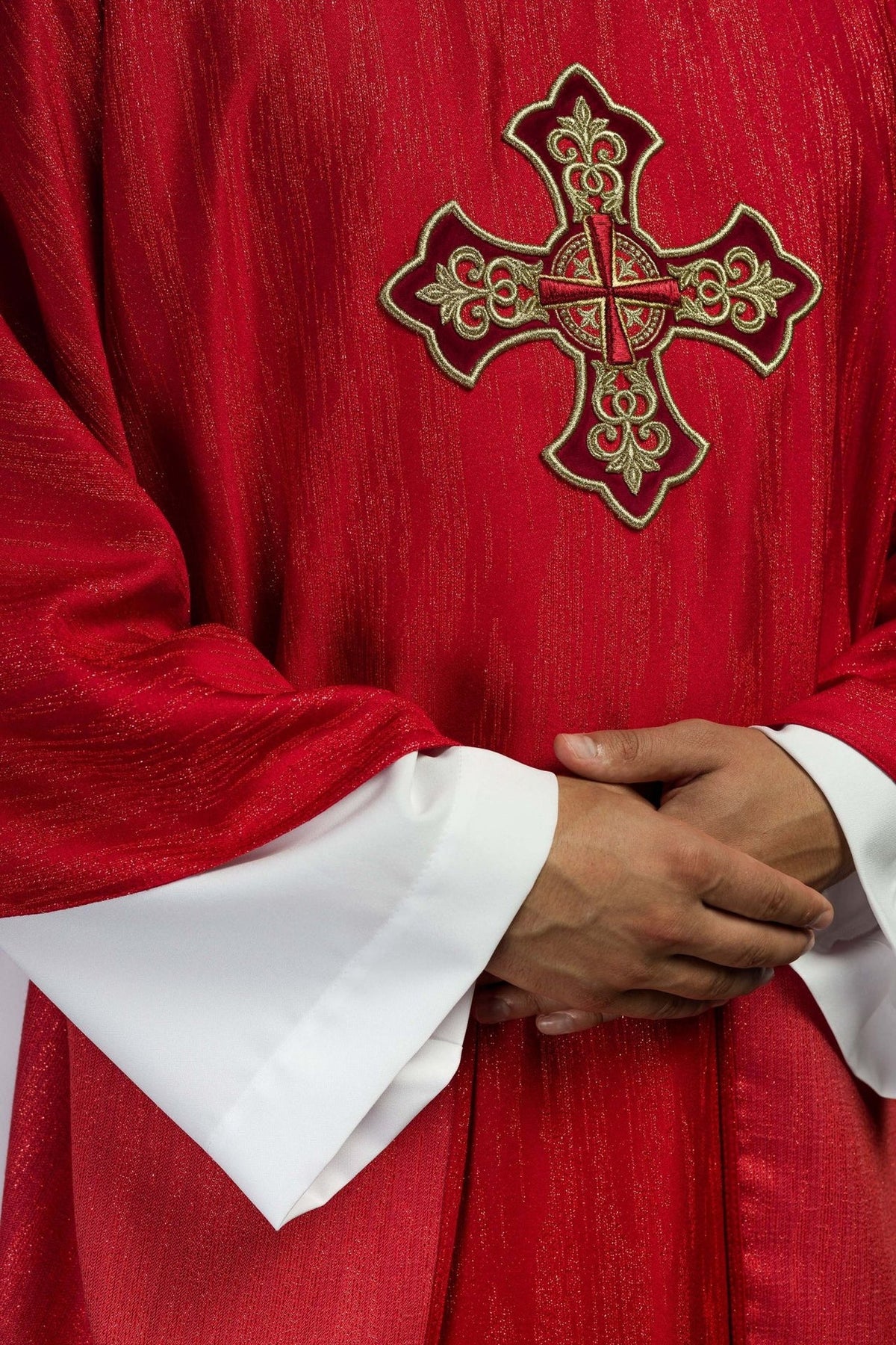 Red chasuble close-up showing gold embroidered cross and textured decorative fabric