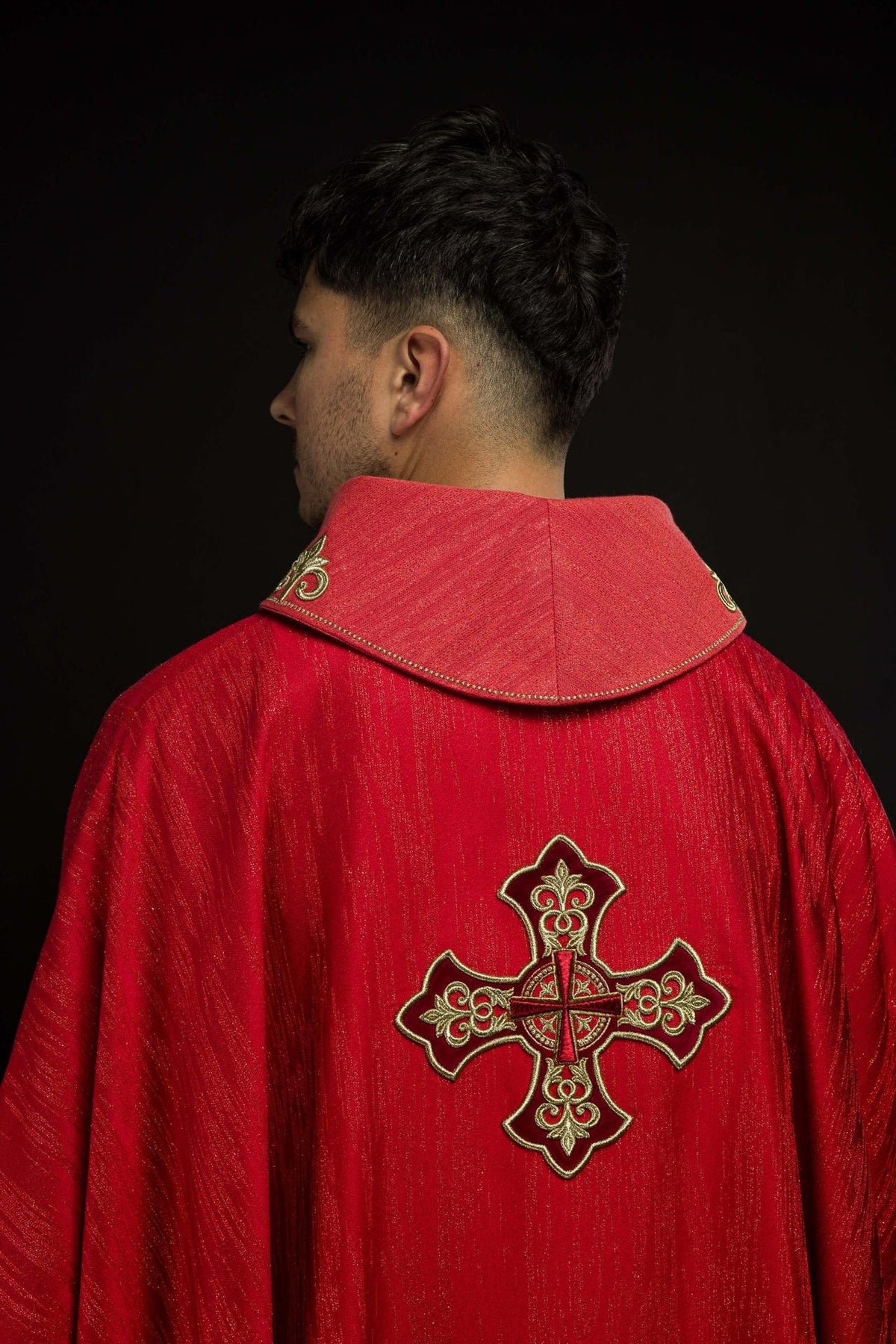 Red chasuble side detail with gold embroidered collar motif and decorative fabric