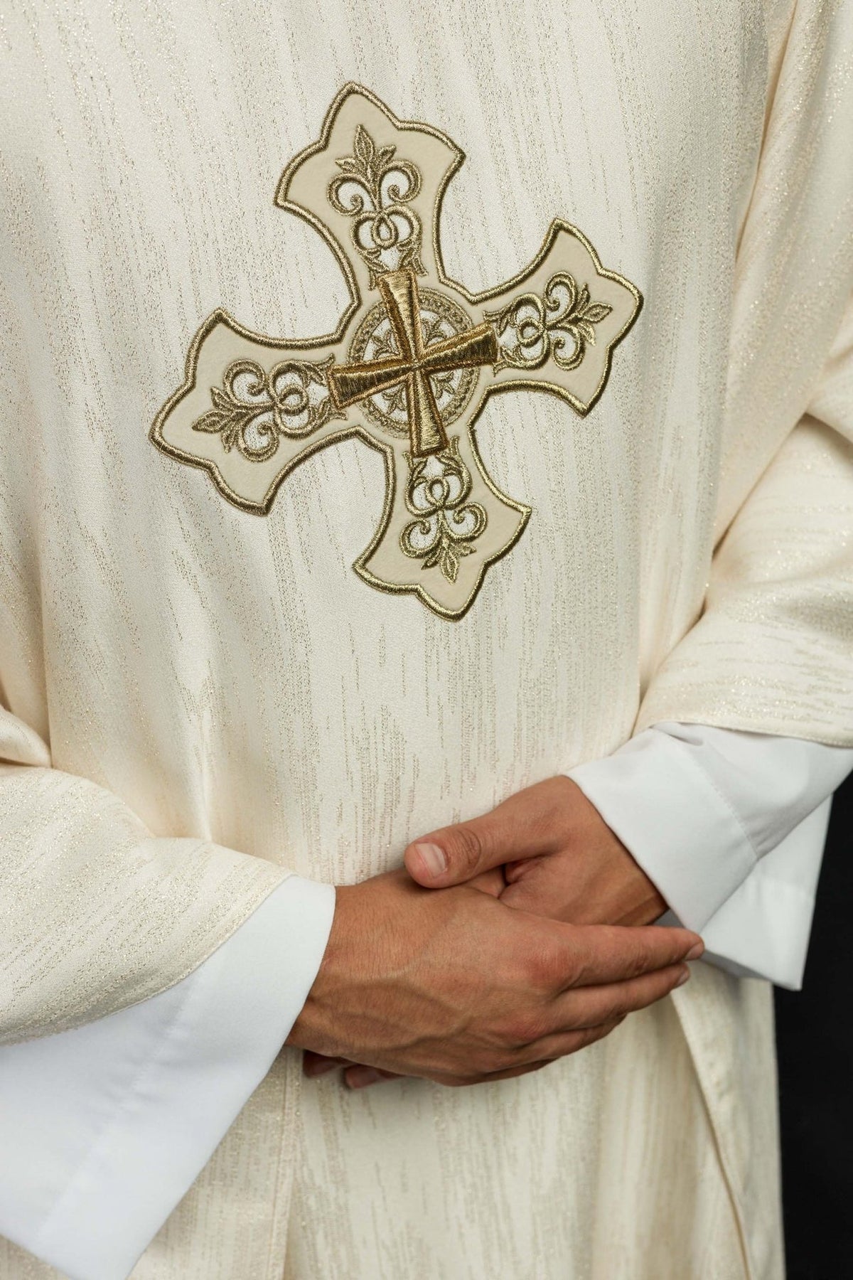 Ecru chasuble close-up showing embroidered gold cross and decorative fabric