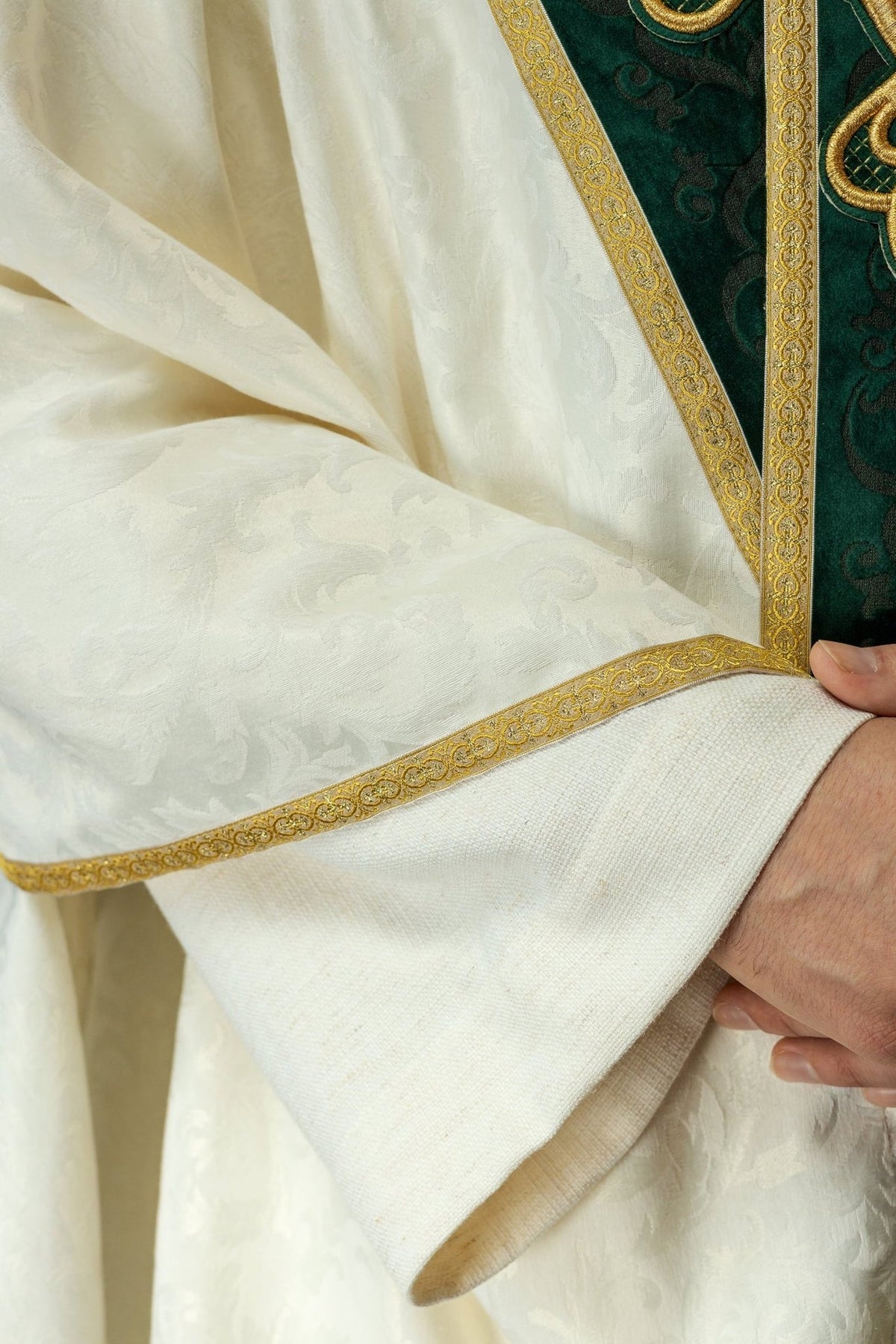 Chasuble close-up showing green velvet orphrey, white jacquard fabric and gold trim