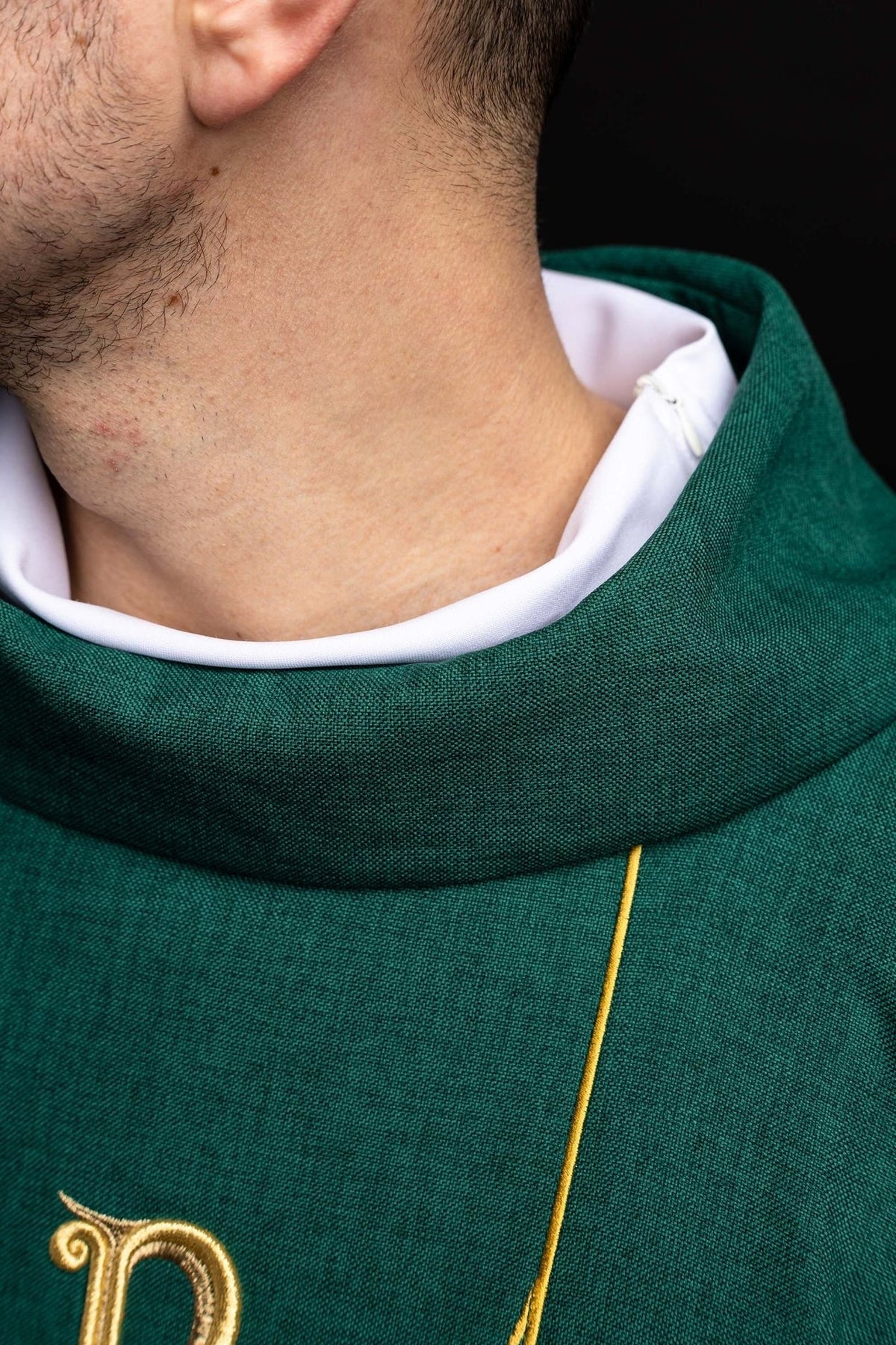 Green chasuble close-up showing stand-up collar, gold trim and embroidered cross