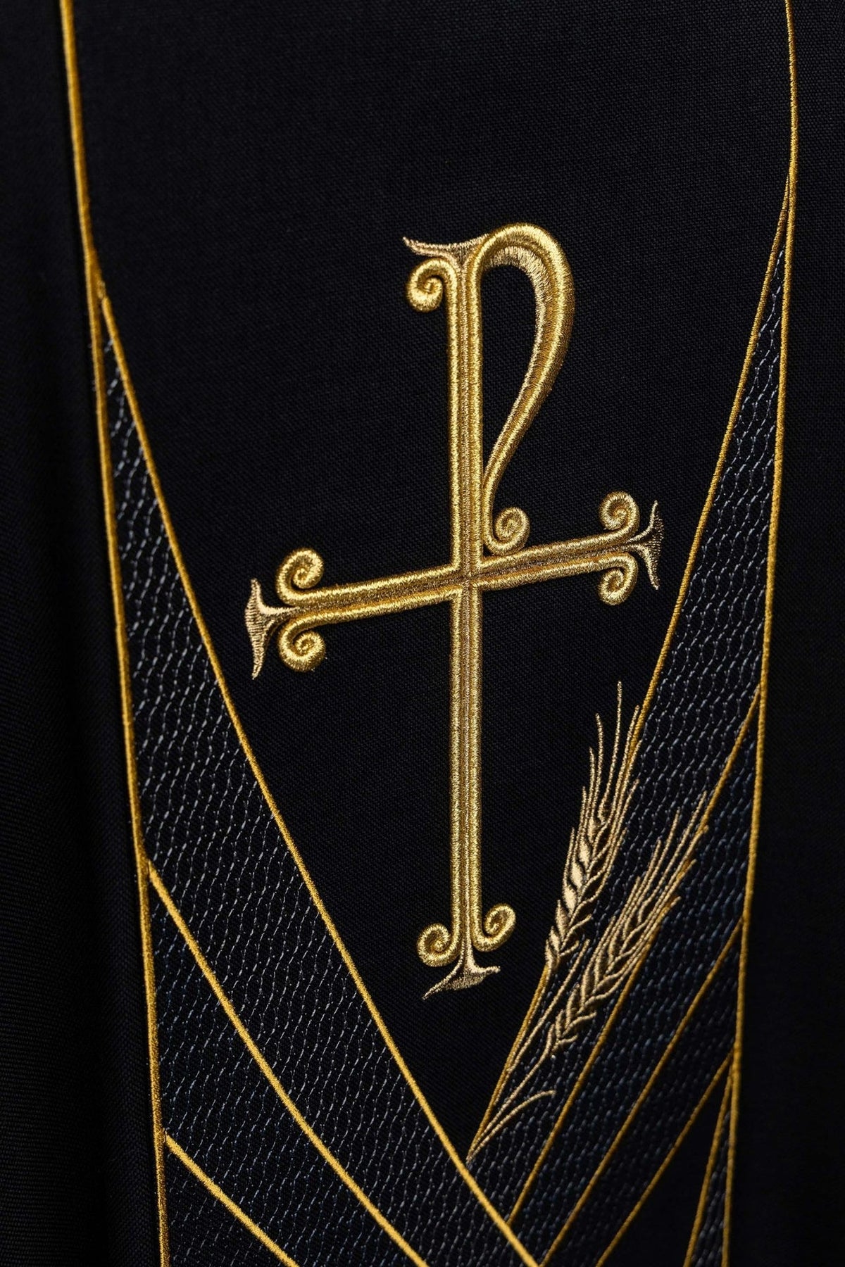 Black chasuble close-up of gold PAX cross and wheat embroidery on the orphrey