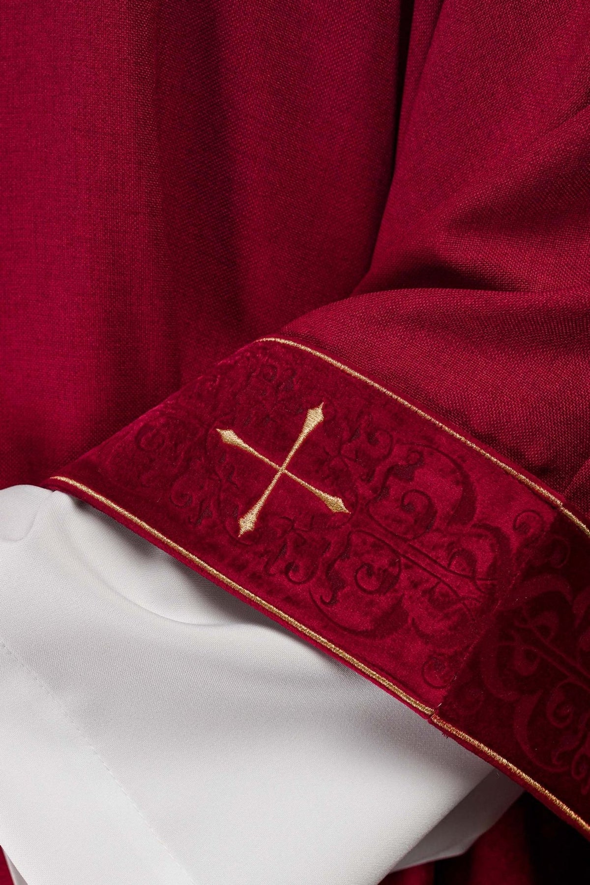 Red chasuble cuff close-up with gold cross and embroidered pattern