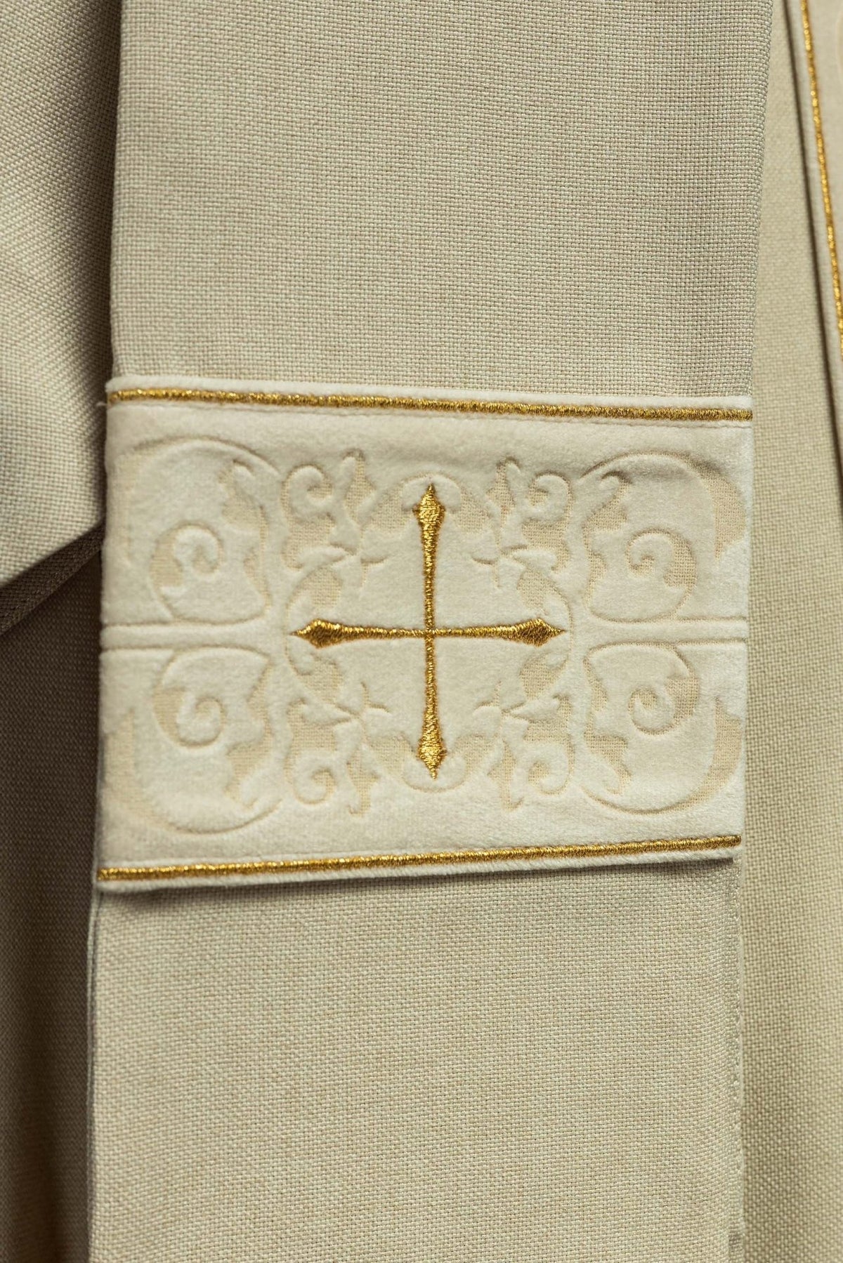 Ecru chasuble sleeve detail with embroidered orphrey and gold cross