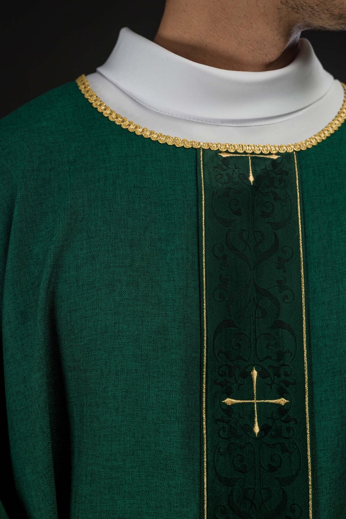 Green chasuble close-up showing embroidered orphrey and gold trim at the collar