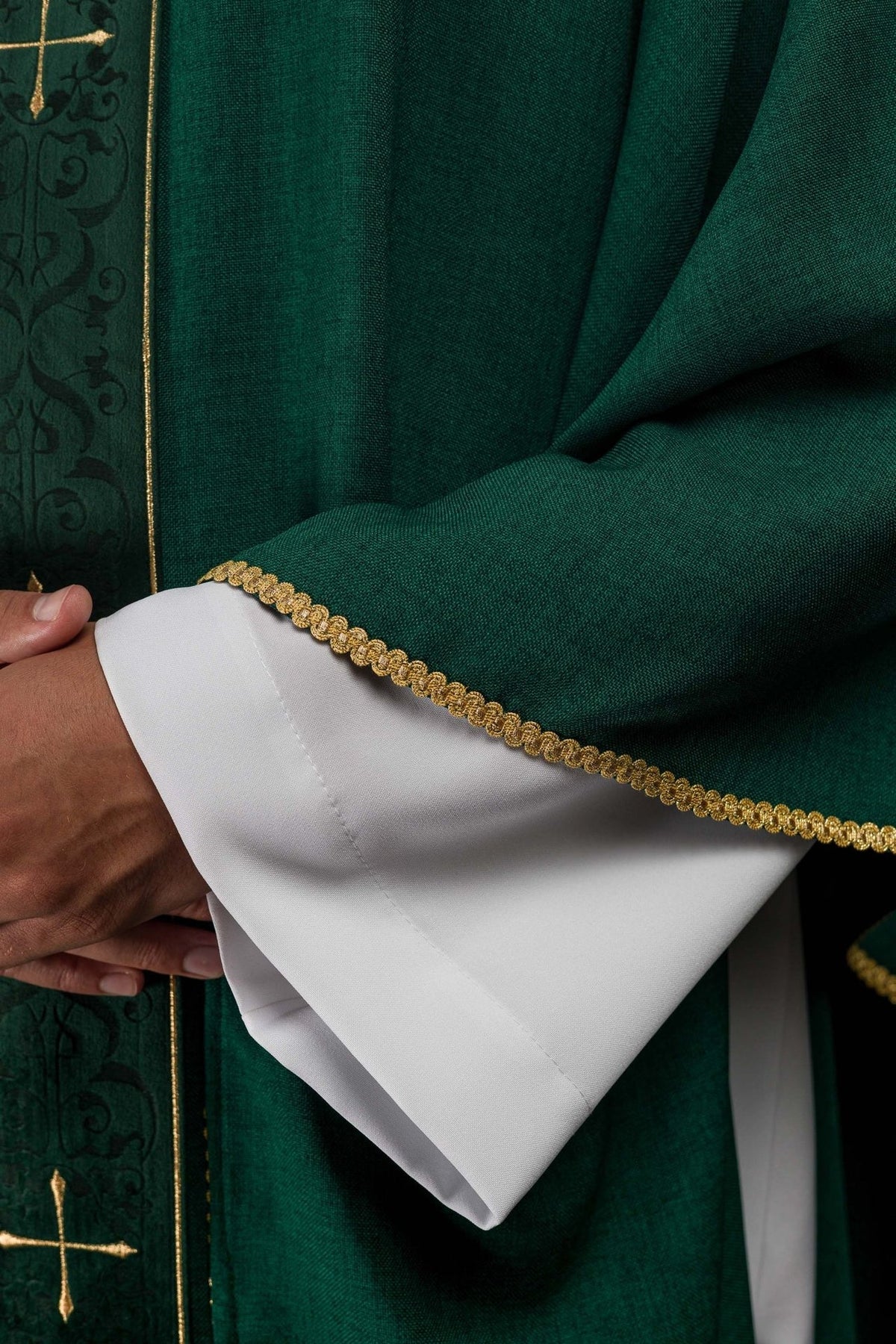 Green chasuble close-up showing gold trim on the sleeve and white cuff