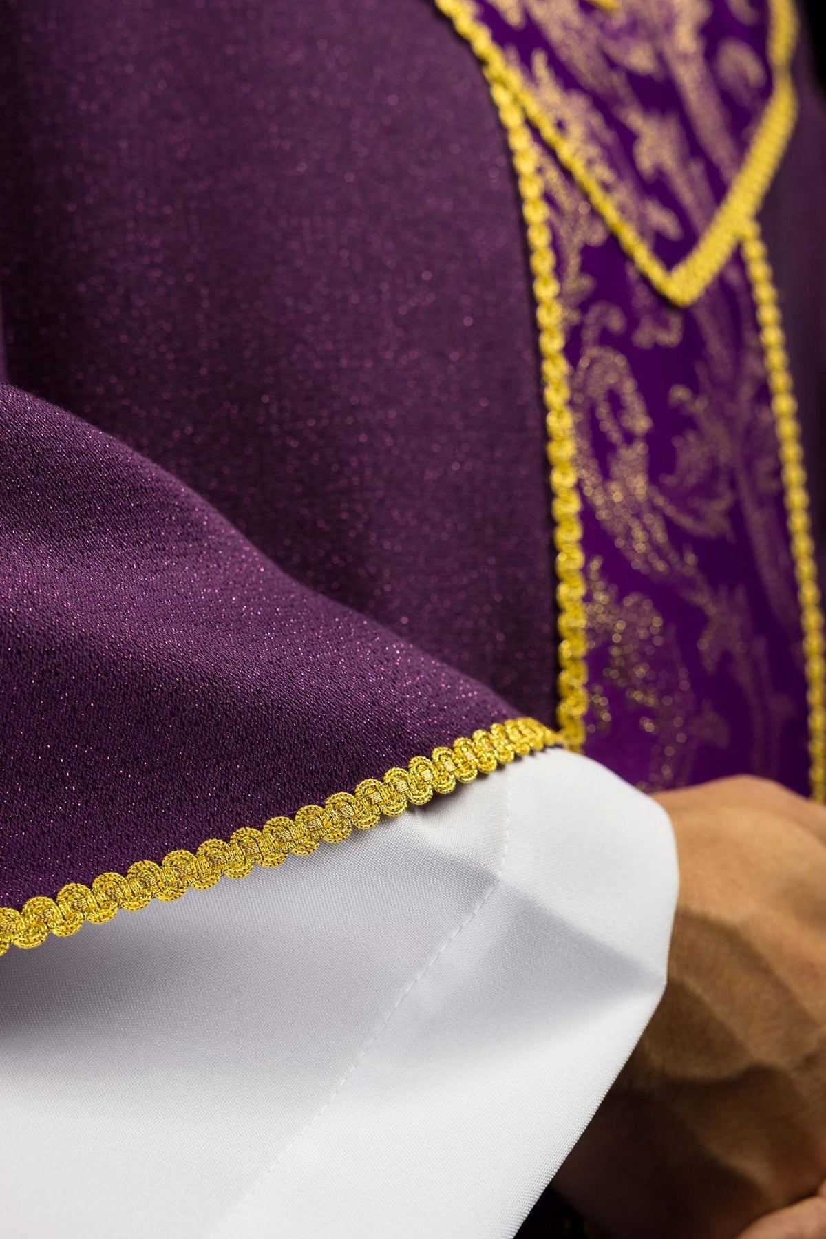 Purple chasuble detail showing gold trim and embroidered jacquard orphrey