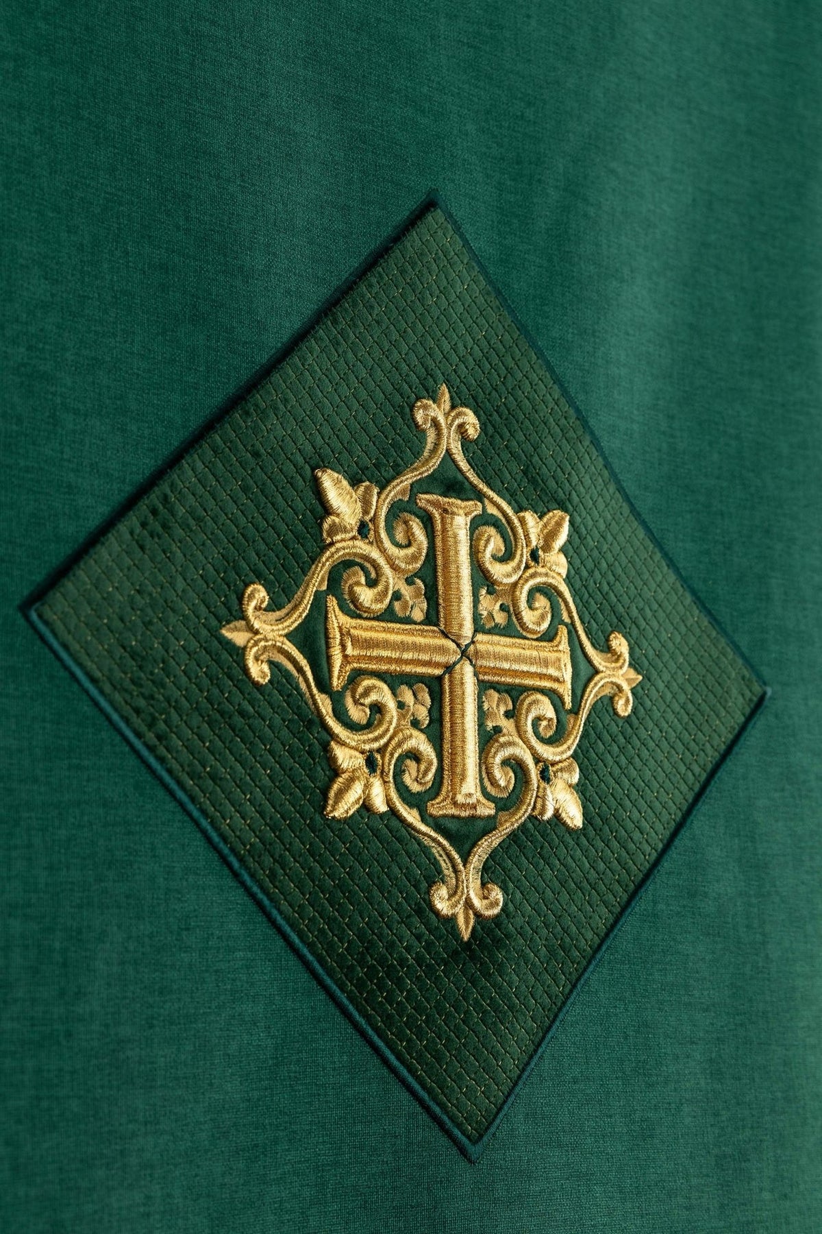 Green church lectern cover close-up showing cross embroidery on a diamond panel