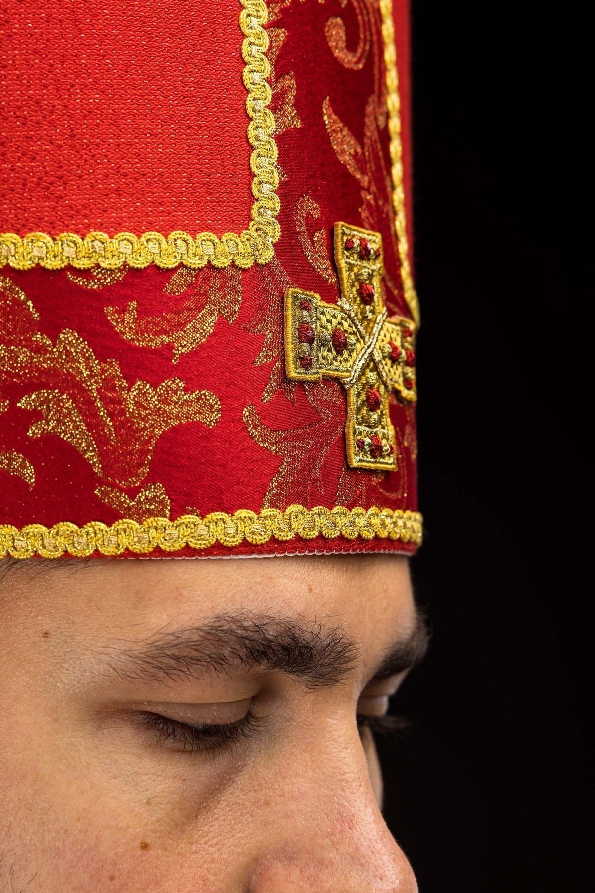 Red miter close-up showing embroidered gold cross, red jacquard and gold trim