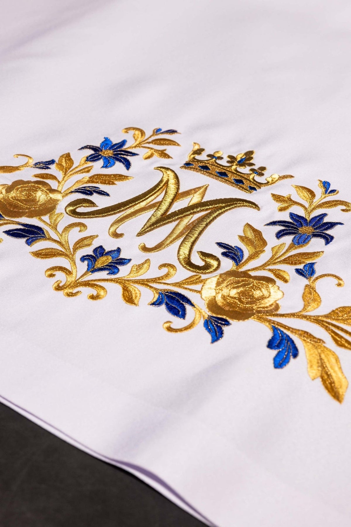 Altar cloth detail showing white fabric with blue and gold floral embroidery