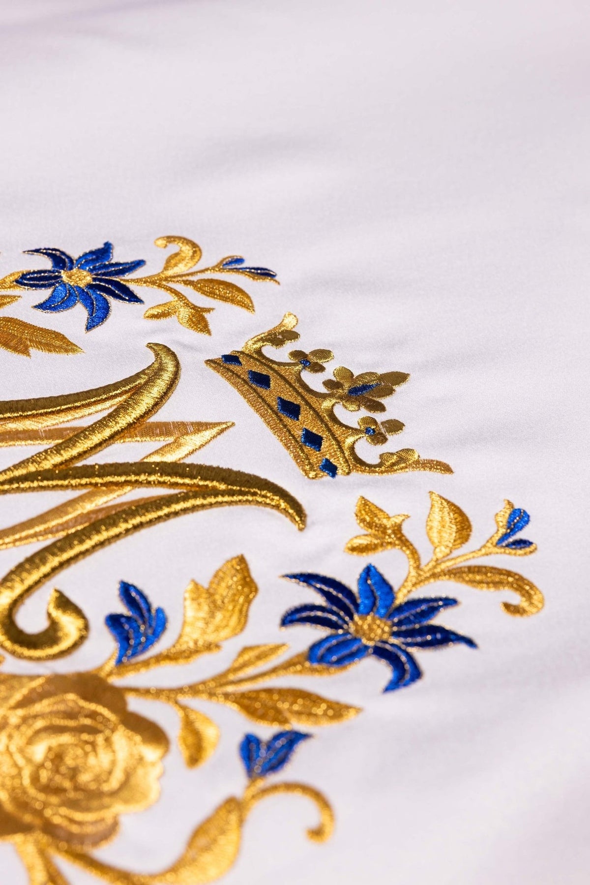 Altar cloth close-up showing crowned Marian symbol in gold embroidery