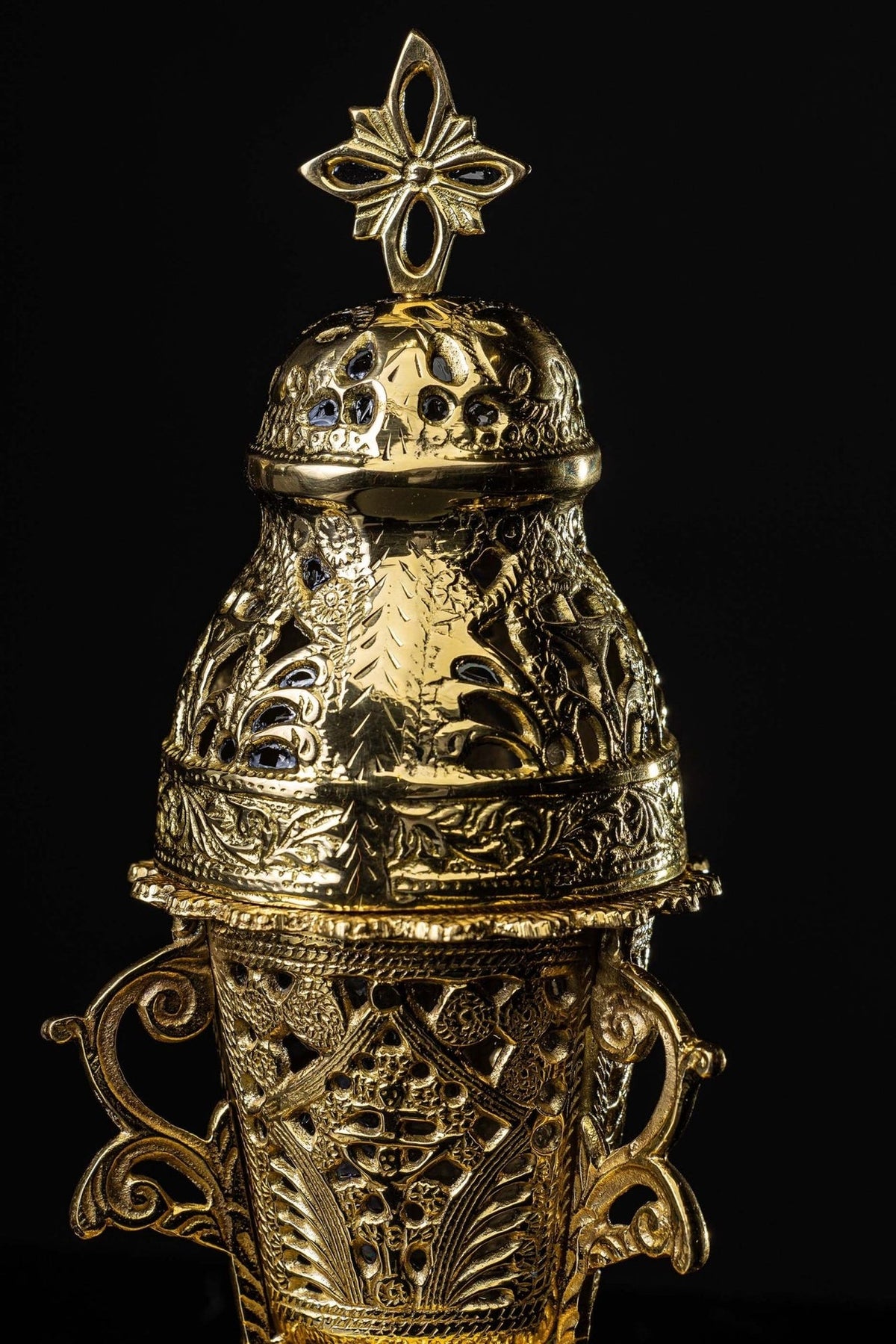 Gold censer close-up showing pierced lid, ornate floral details and cross