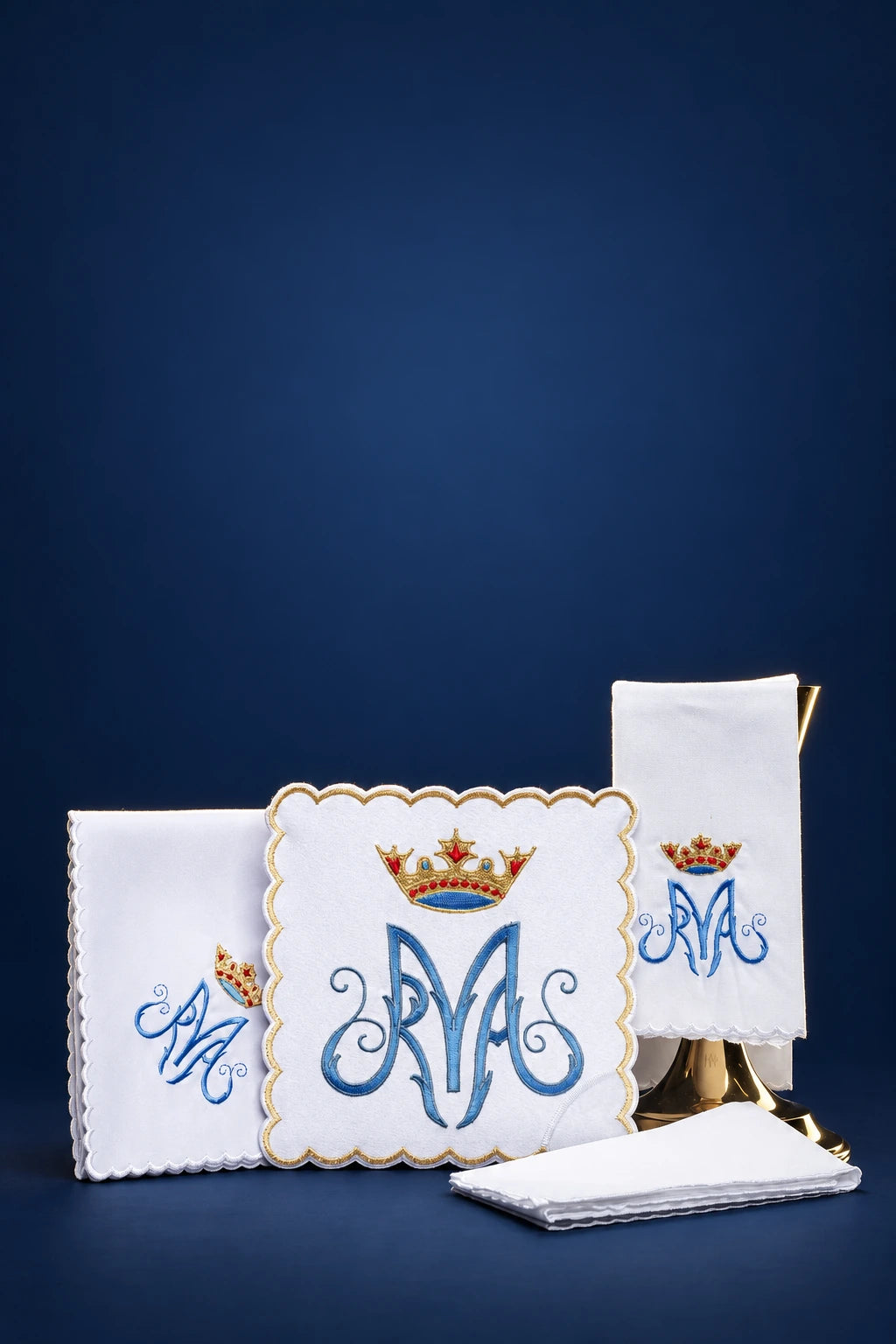Marian altar linen set with blue monogram and crown embroidery, including folded cloths and a cover cloth