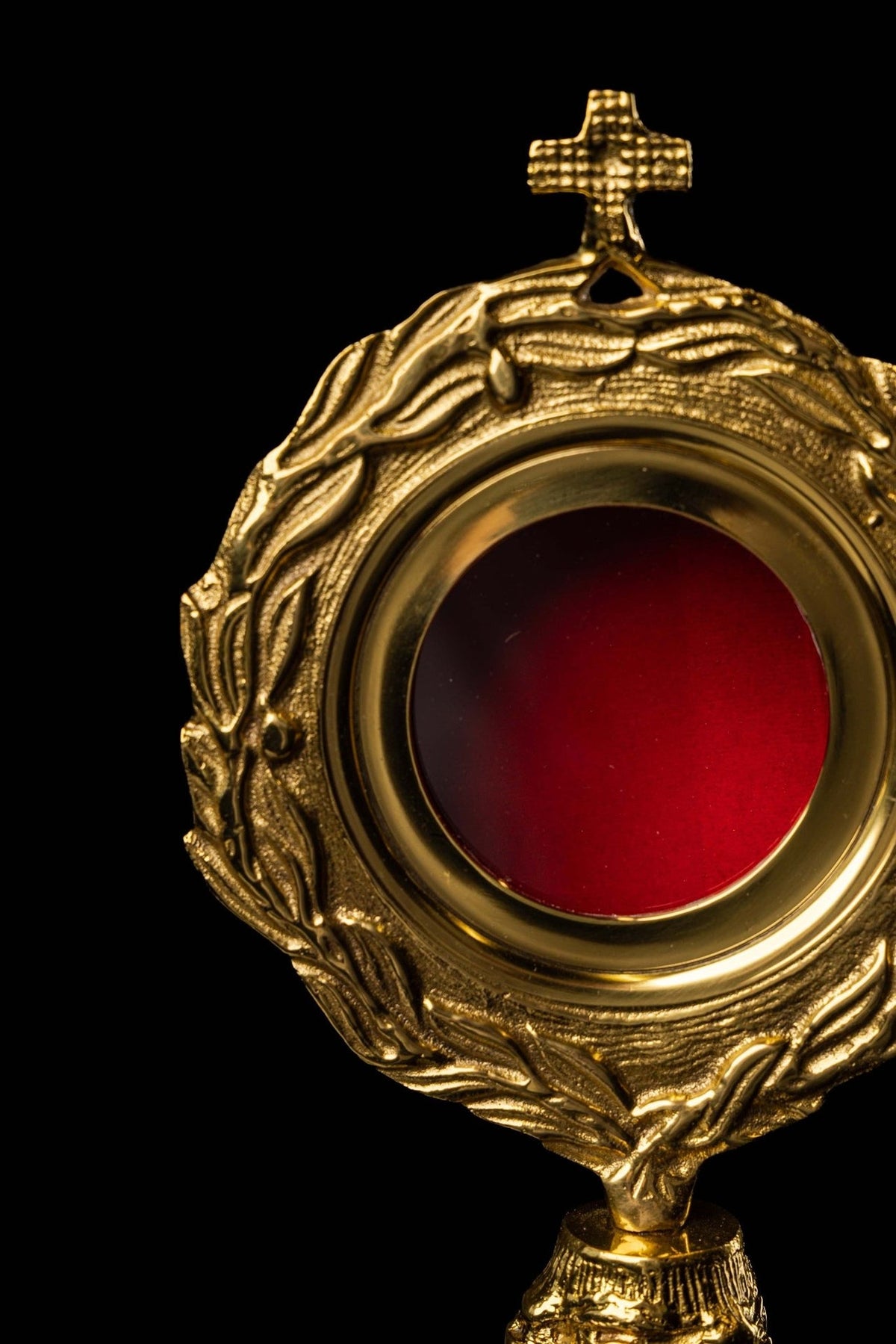 Brass reliquary close-up showing wreath motif, red center and ornate stand