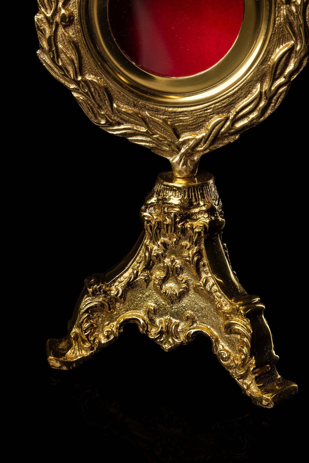 Brass reliquary lower detail showing wreath tip and ornate stand