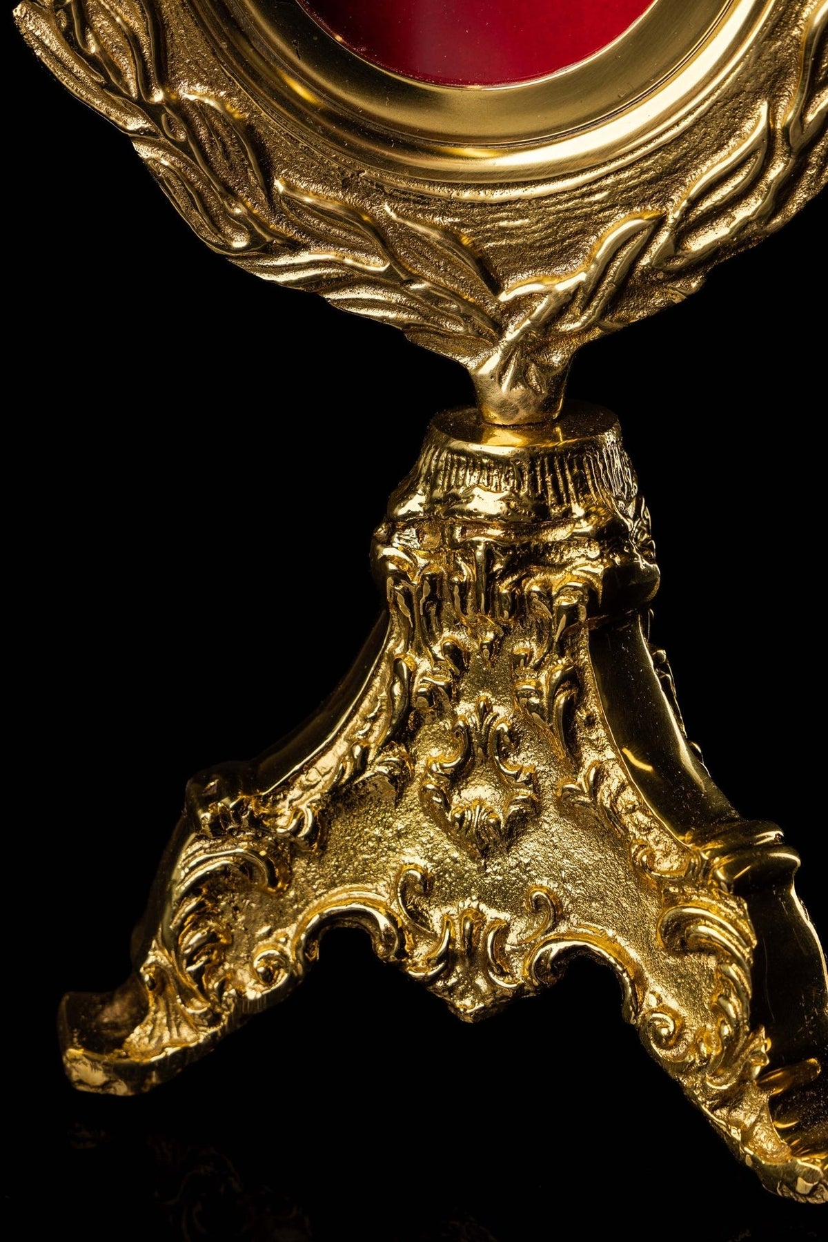 Brass reliquary stand close-up with ornate scrollwork and three feet