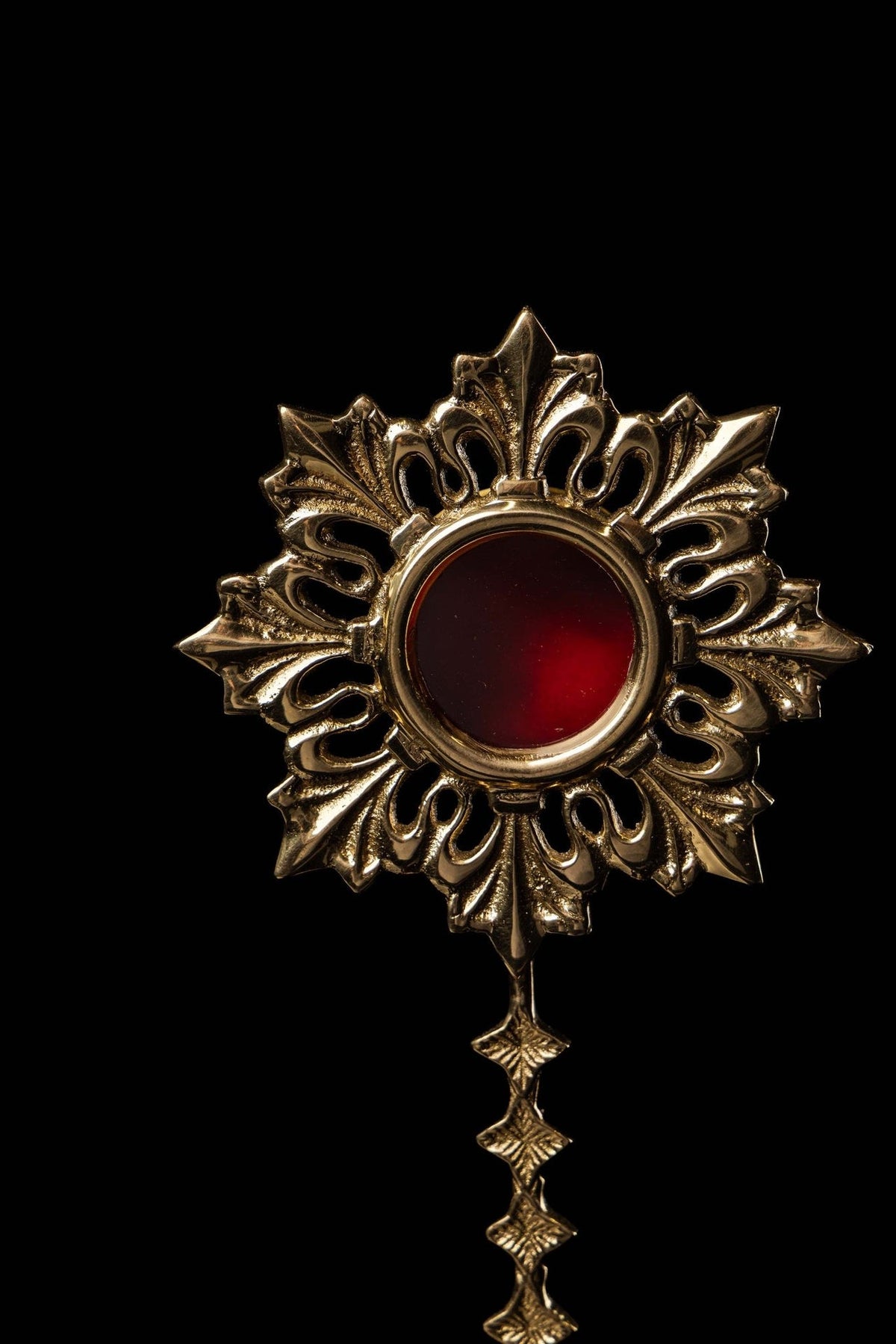 Brass reliquary sunburst front close-up with red center and radiating leaf motifs