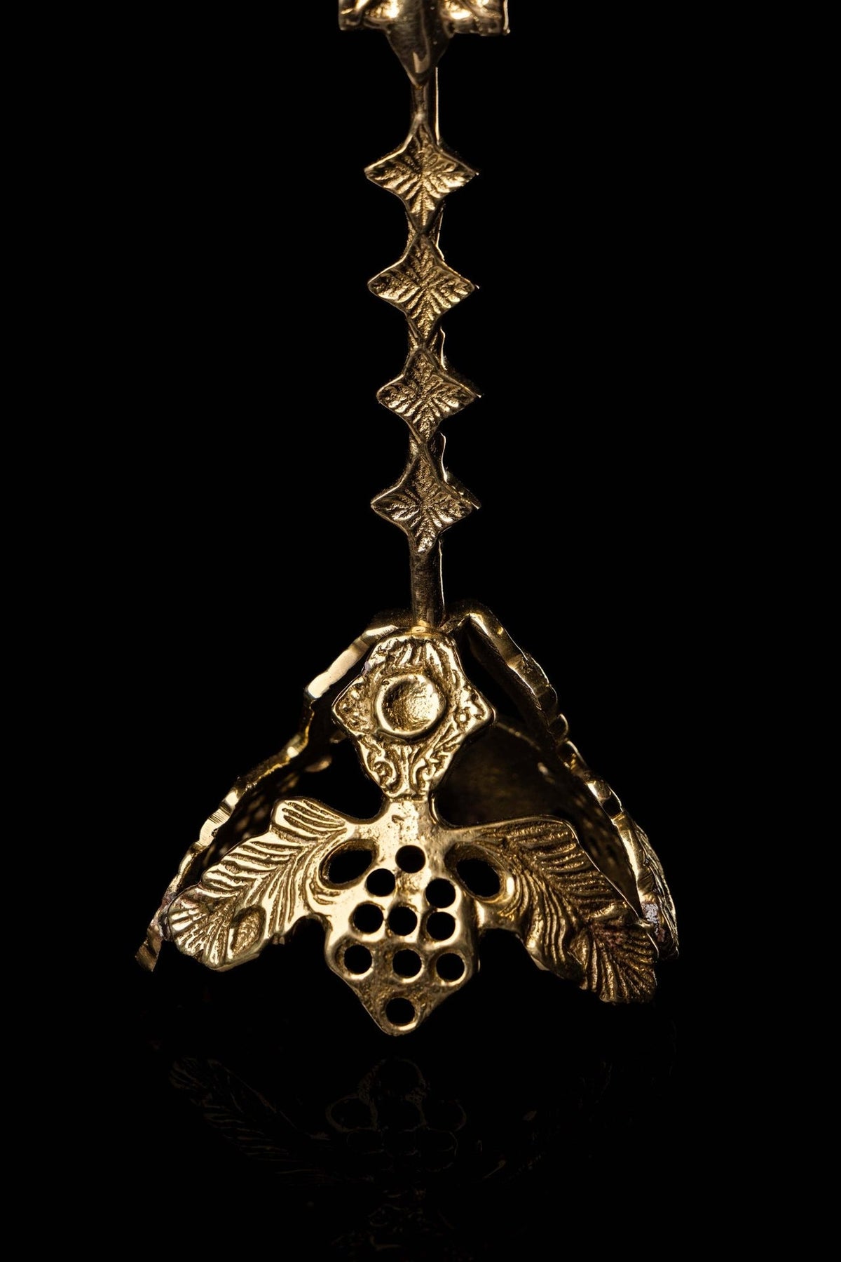 Brass reliquary base close-up with grape cluster, leaves and perforated decorative design